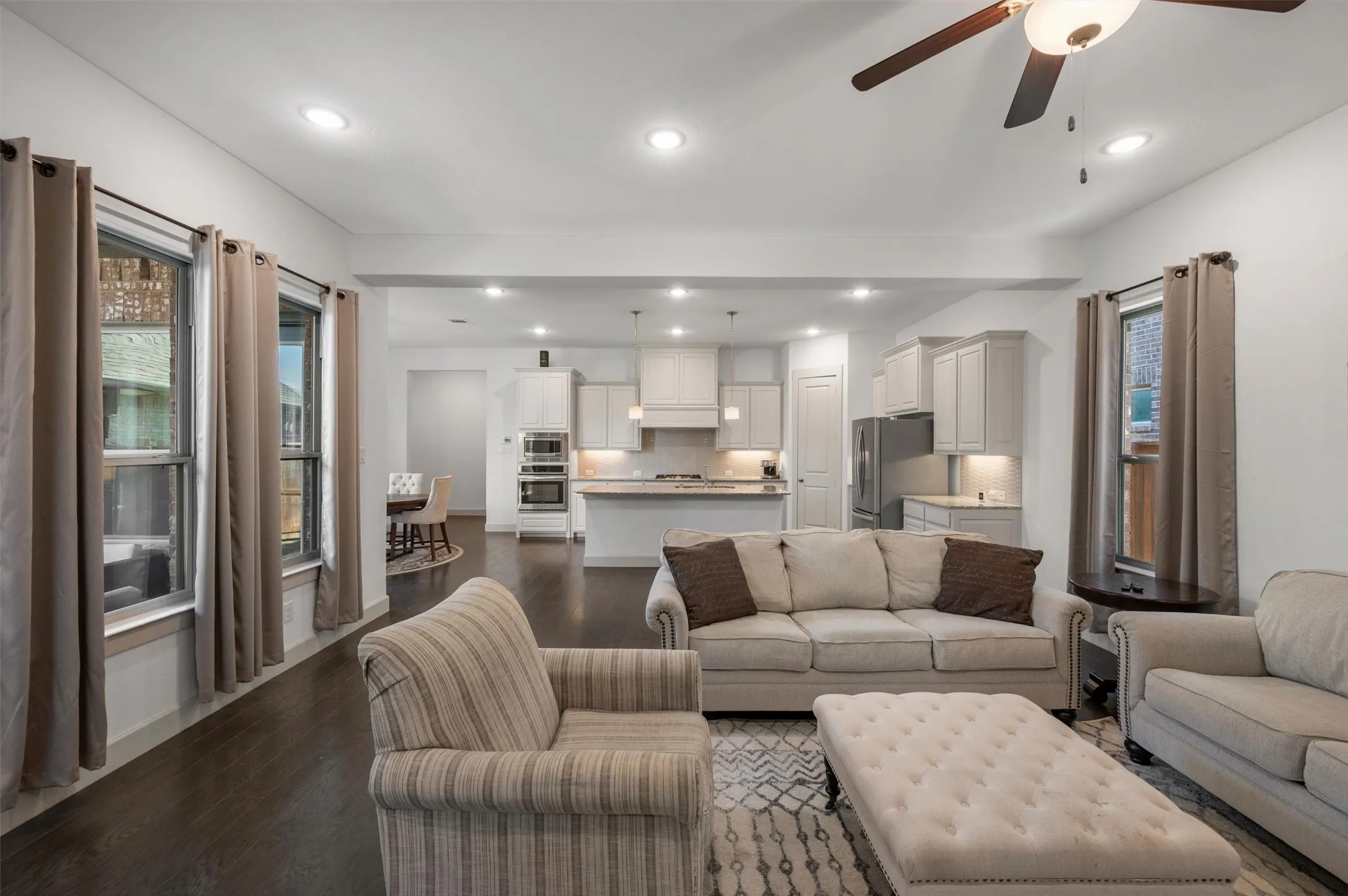 Recessed lighting, wood-finish flooring, white cabinetry, stainless steel appliances, and a ceiling fan with integrated lighting