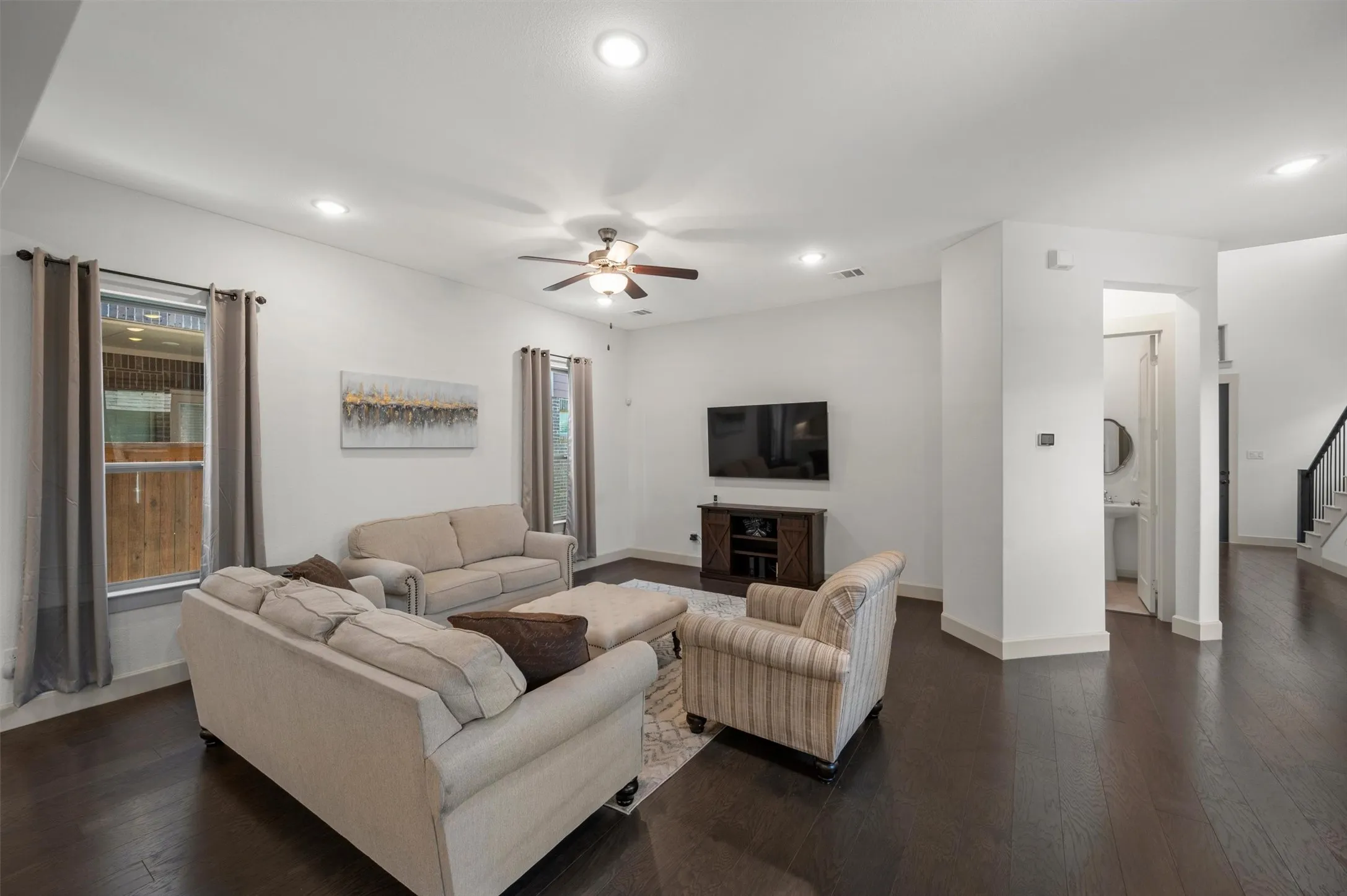 Spacious living area featuring dark wood-finish flooring, recessed lighting, and a ceiling fan