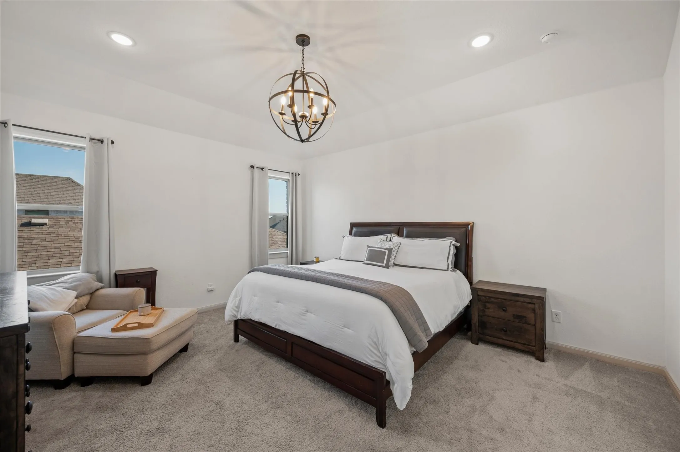 Tray ceiling with recessed lighting, central orb chandelier, light gray carpeting, and multiple windows