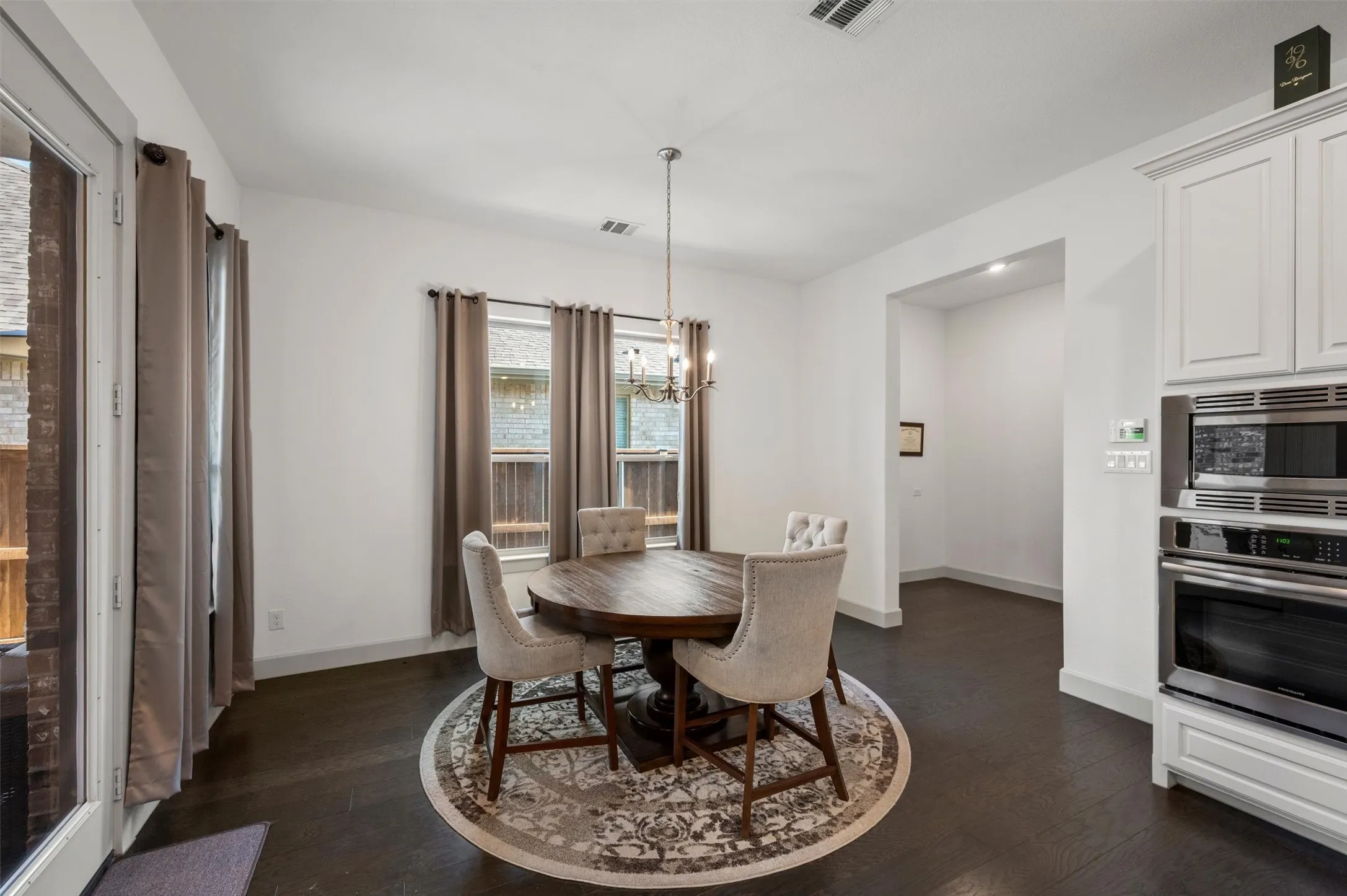 Recessed lighting, wood-finish flooring, white cabinetry, built-in stainless steel appliances, and a glass-paneled exterior door