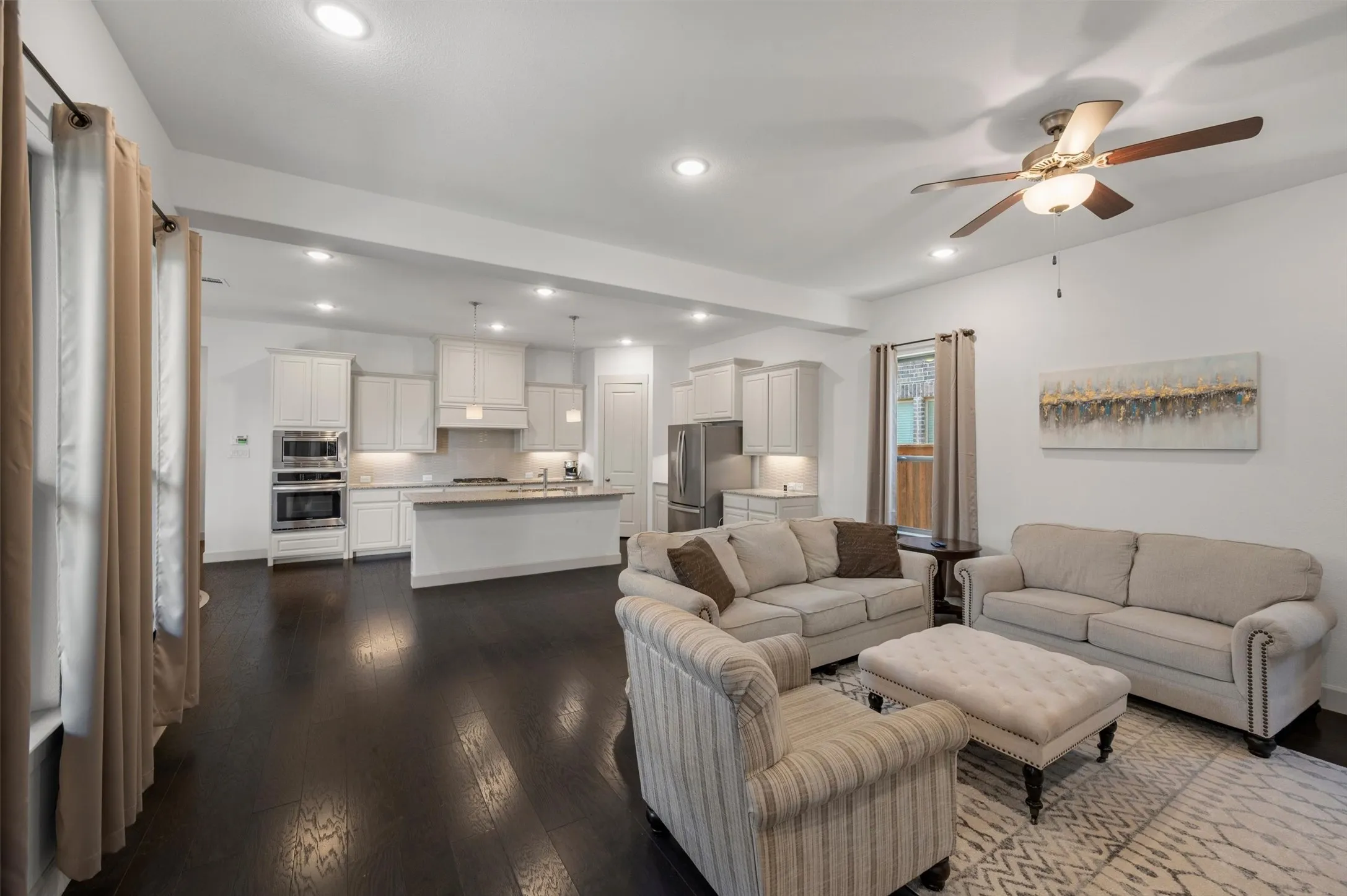 Open-concept living area featuring dark wood-finish flooring, recessed lighting, and a ceiling fan