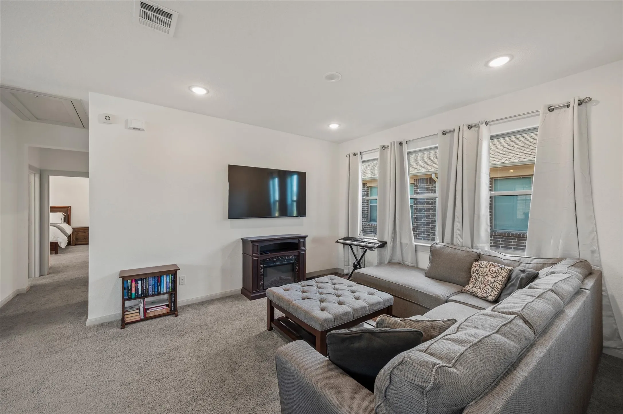 Recessed lighting, grey carpeting, a built-in electric fireplace, and multiple windows