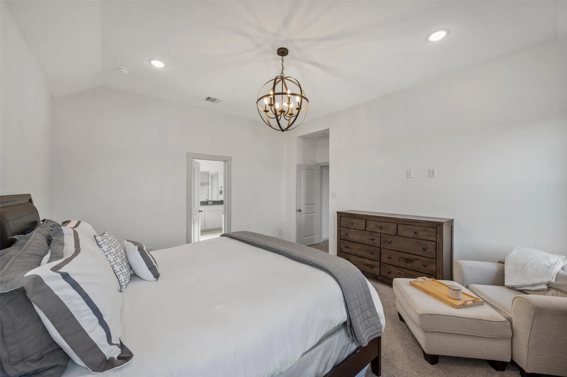 Vaulted ceiling with recessed lighting and a decorative chandelier