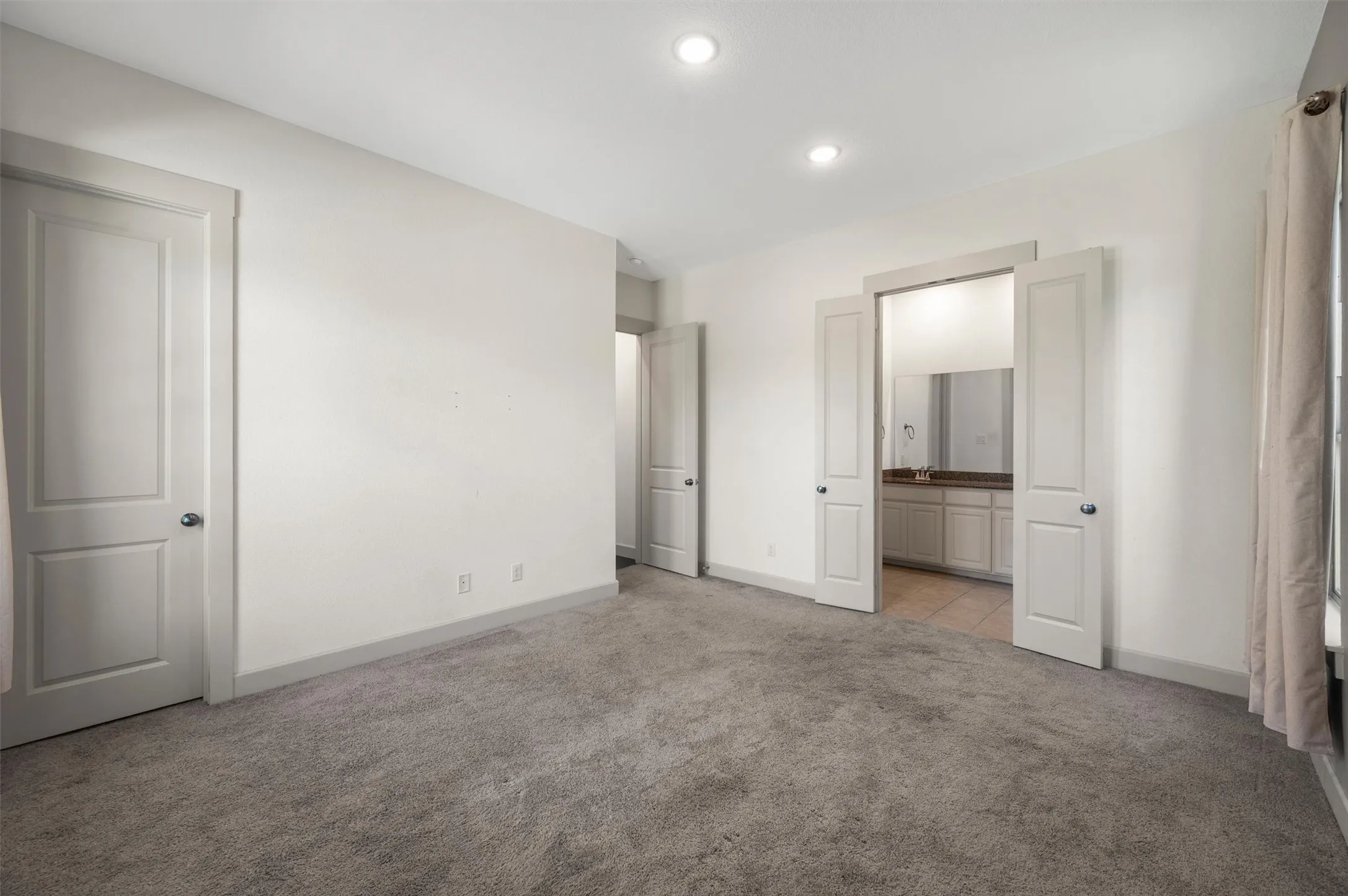 Recessed lighting illuminates the room, featuring a carpeted floor and painted walls