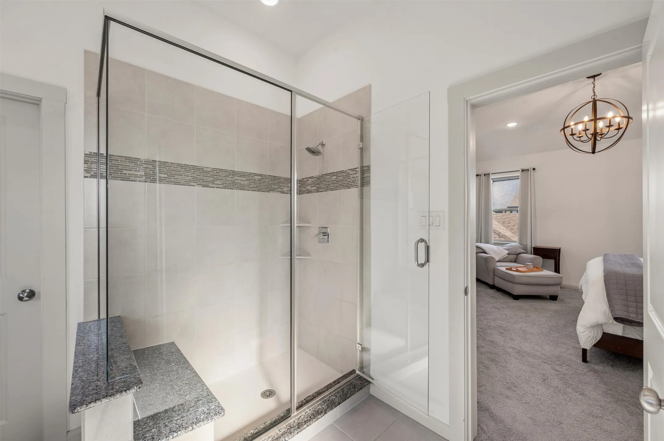 Glass-enclosed shower with a tiled surround featuring a decorative mosaic accent