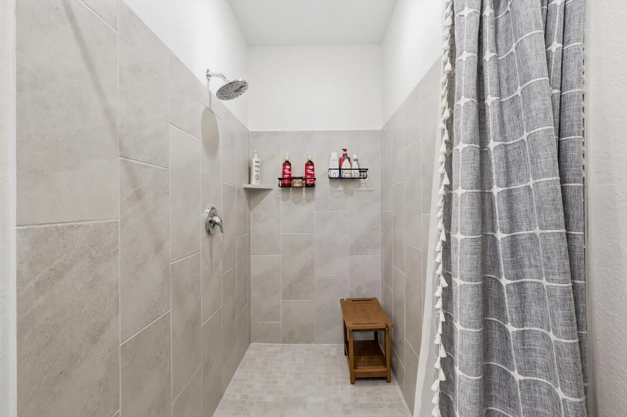Walk-in shower featuring large format wall tiles, a mosaic tile floor, and a rainfall showerhead