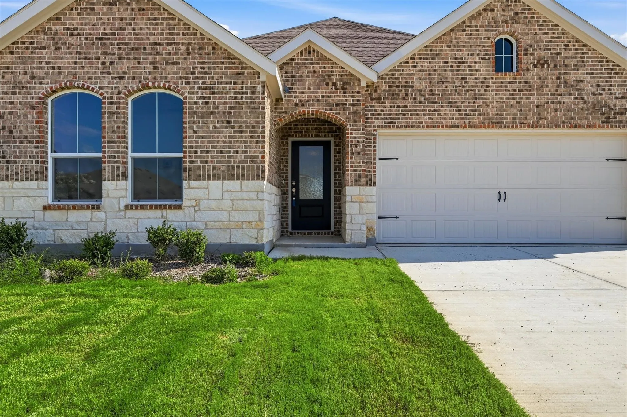 Brick and stone facade featuring arched windows and an arched entry