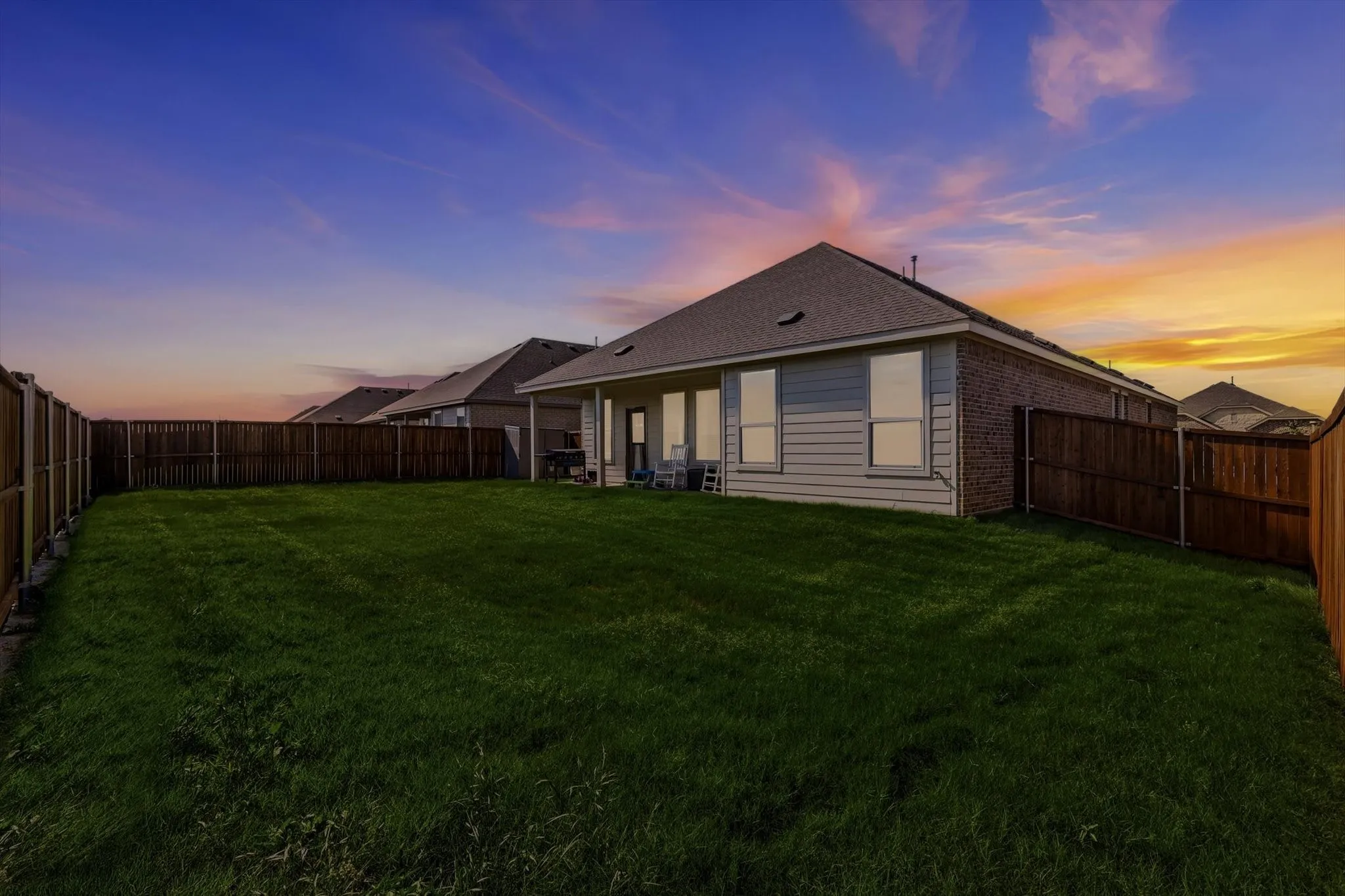 Expansive backyard featuring a manicured lawn, full perimeter privacy fencing, and an extended concrete patio