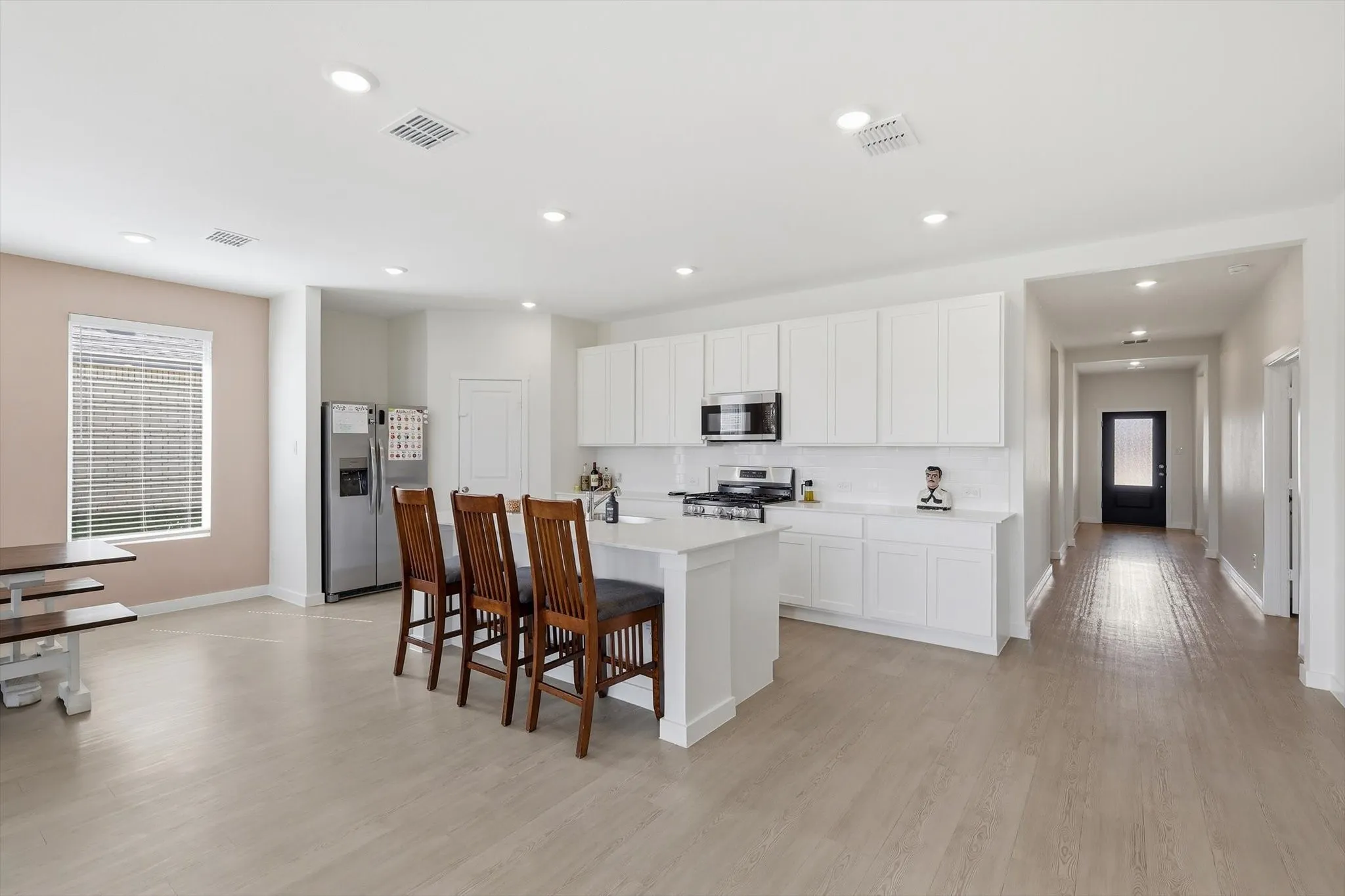 Contemporary kitchen featuring white cabinetry, a central island with countertop seating, stainless steel appliances, and recessed lighting