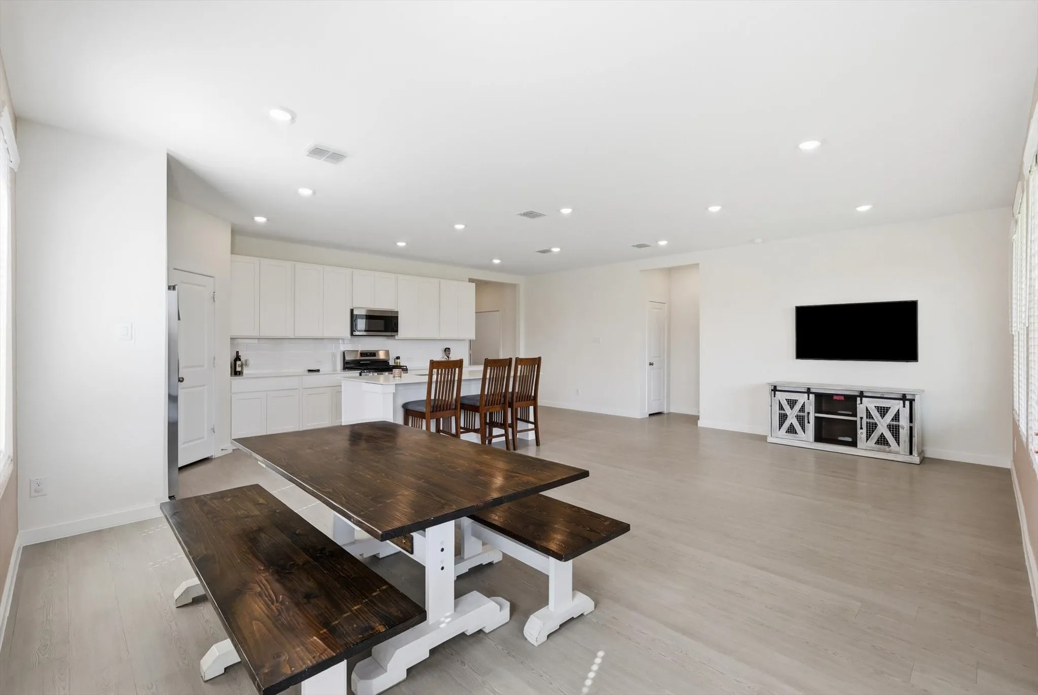 Open-concept living space featuring light wood-finish flooring, recessed lighting, and white walls