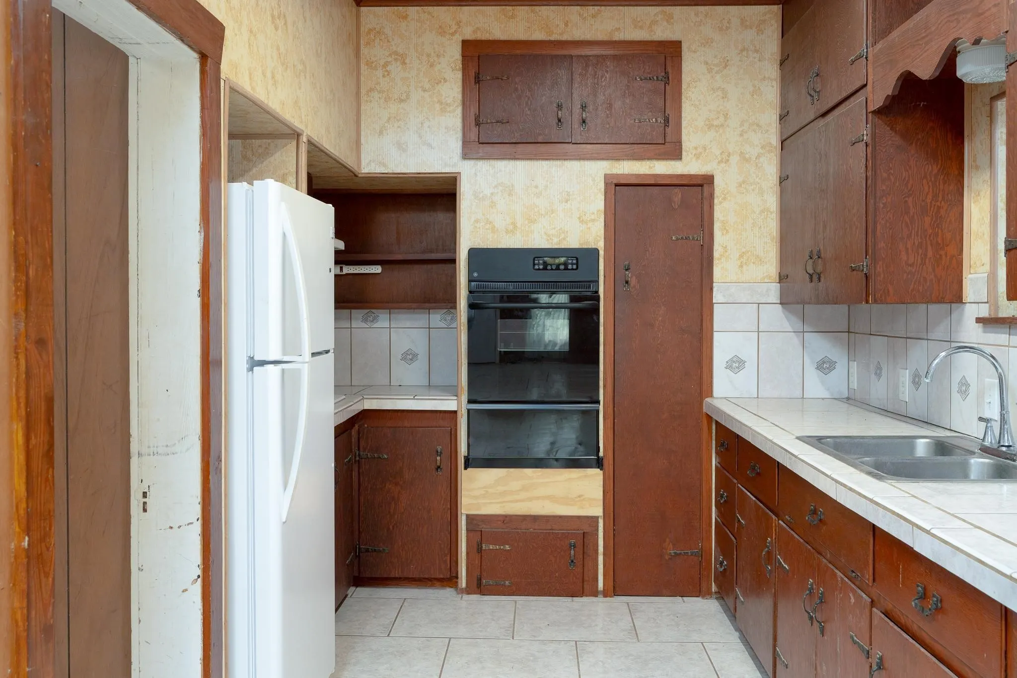 Kitchen featuring wood-finish cabinetry, built-in double oven, tiled backsplash, and light-toned countertops