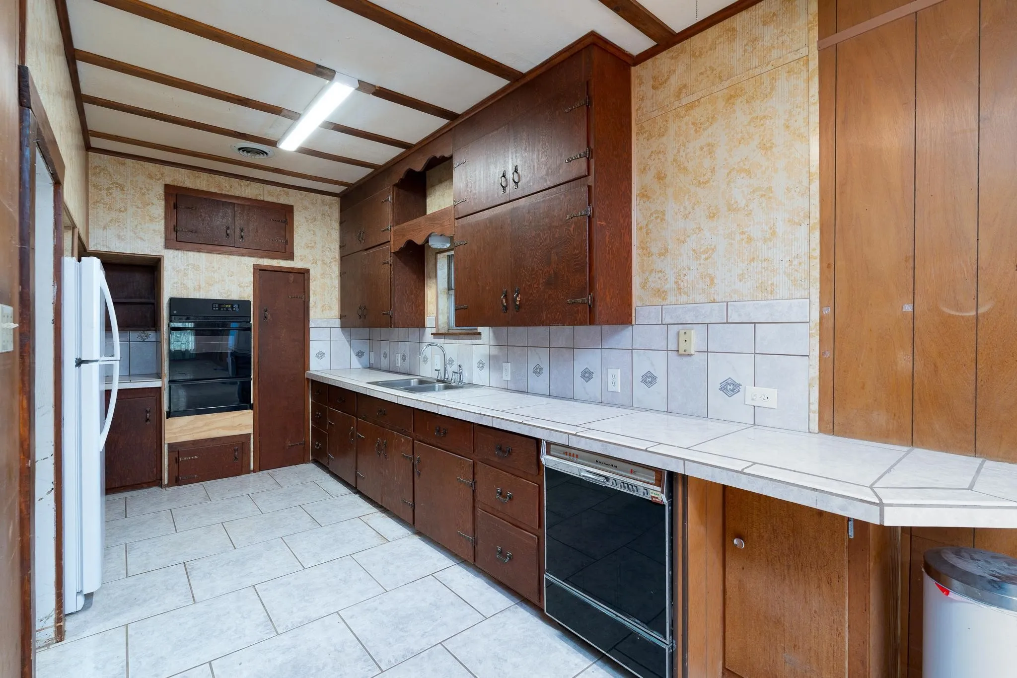 Kitchen featuring wood cabinetry, white tile countertops, a built-in double oven, and tiled flooring