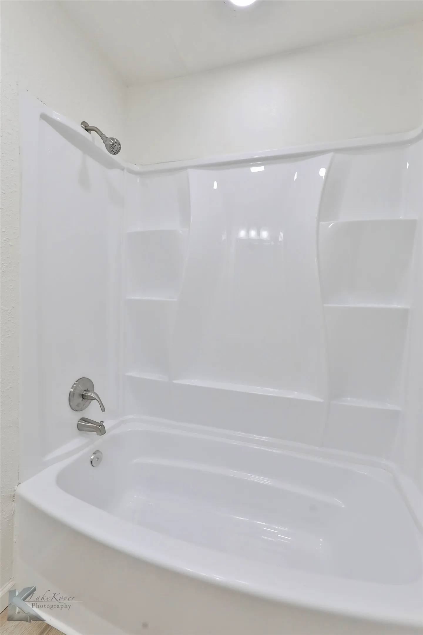 White tub and shower combination unit featuring an integrated shower head and coordinating tub spout