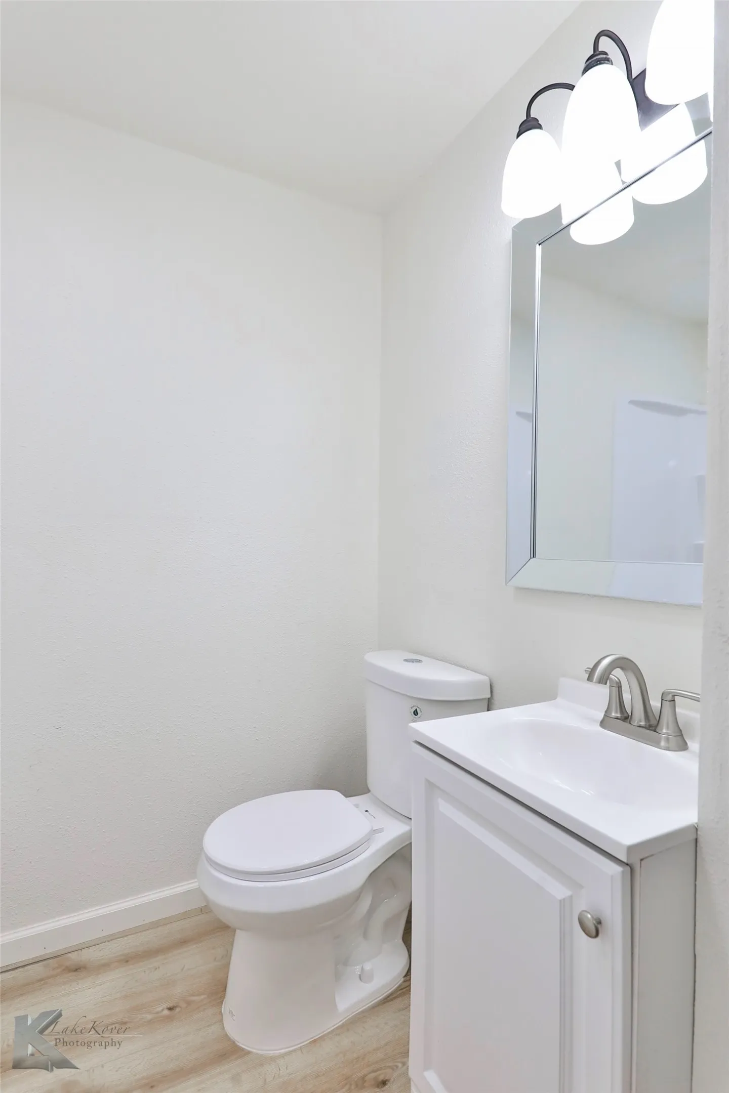 Bathroom featuring a white vanity with integrated sink, brushed nickel faucet, framed mirror, and three-light fixture