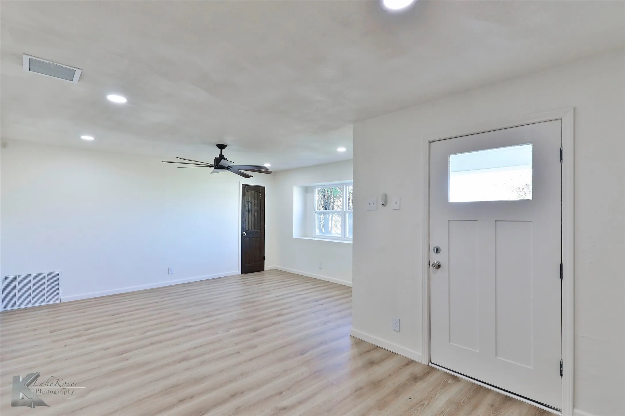 Spacious living area featuring light wood-finish flooring, recessed lighting, and a contemporary ceiling fan