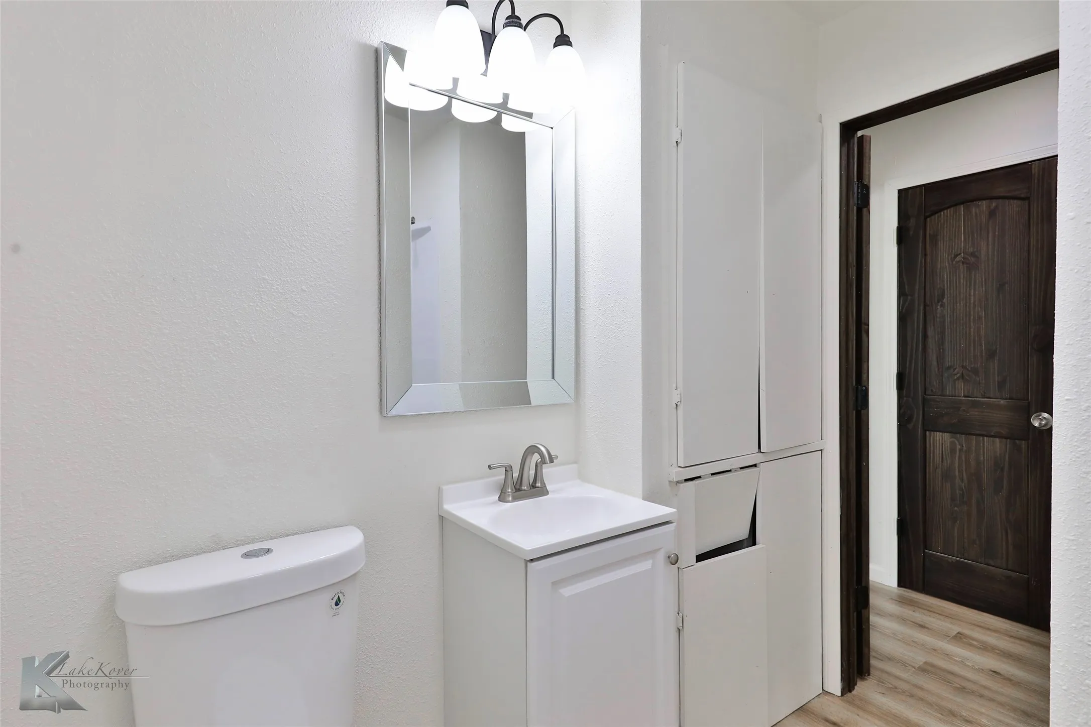 Bathroom featuring a white vanity with integrated sink, chrome faucet, and rectangular framed mirror