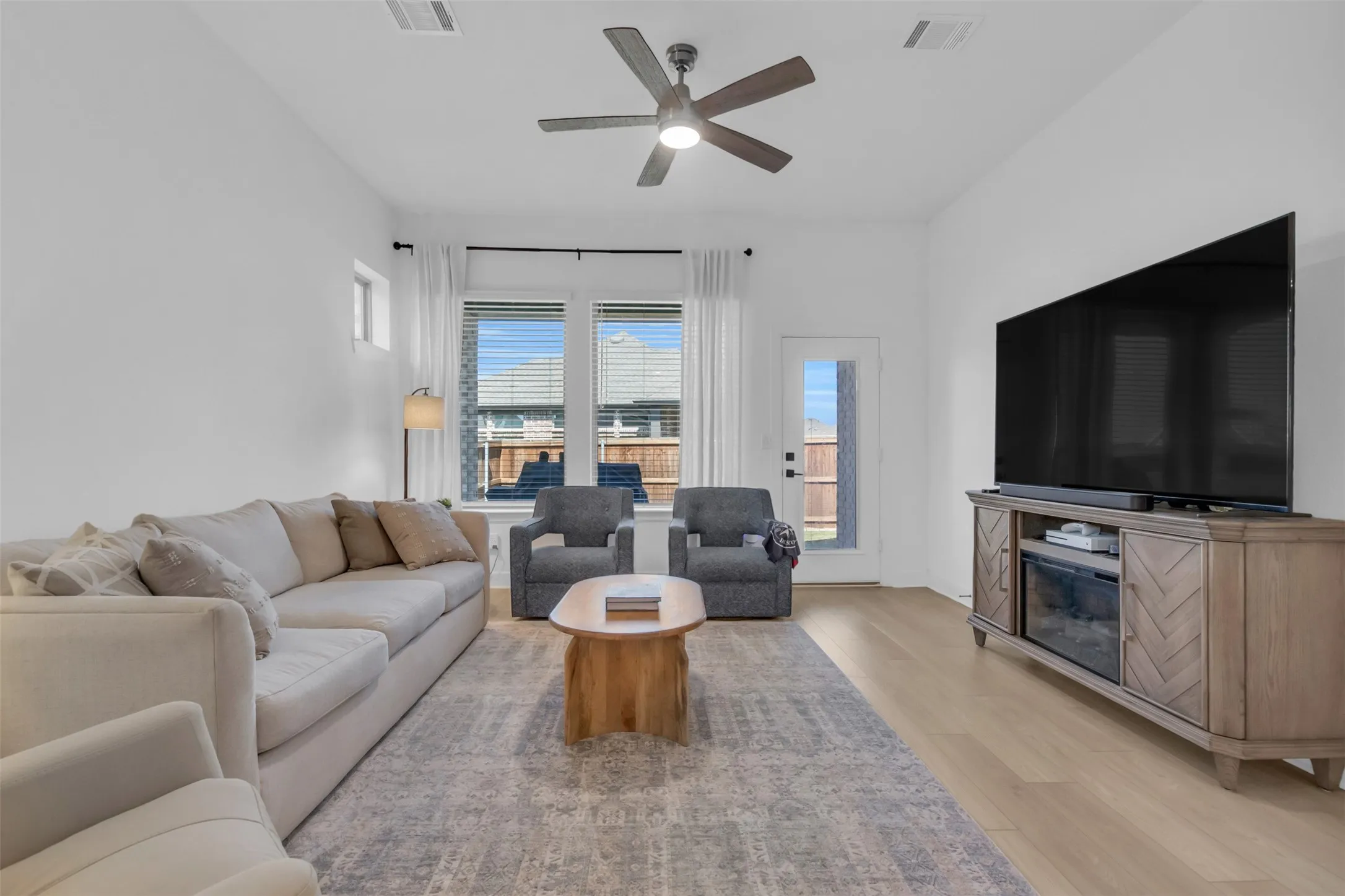 Bright living space featuring light wood-finish flooring, recessed lighting, and a modern ceiling fan