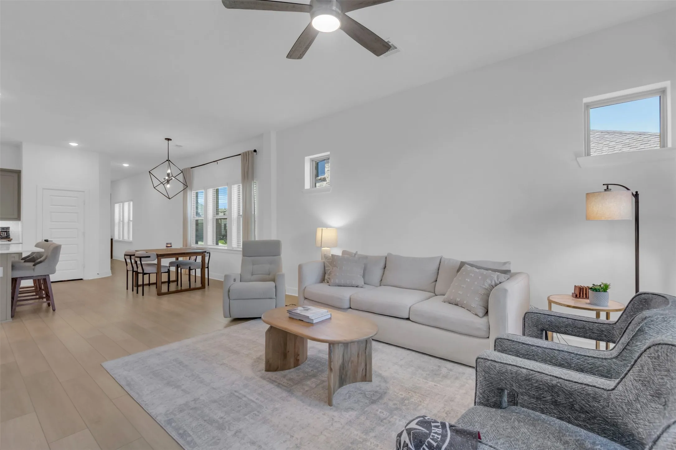 Open-concept living space featuring wood-finish flooring, a contemporary ceiling fan, recessed lighting, and a dining area with a geometric pendant light