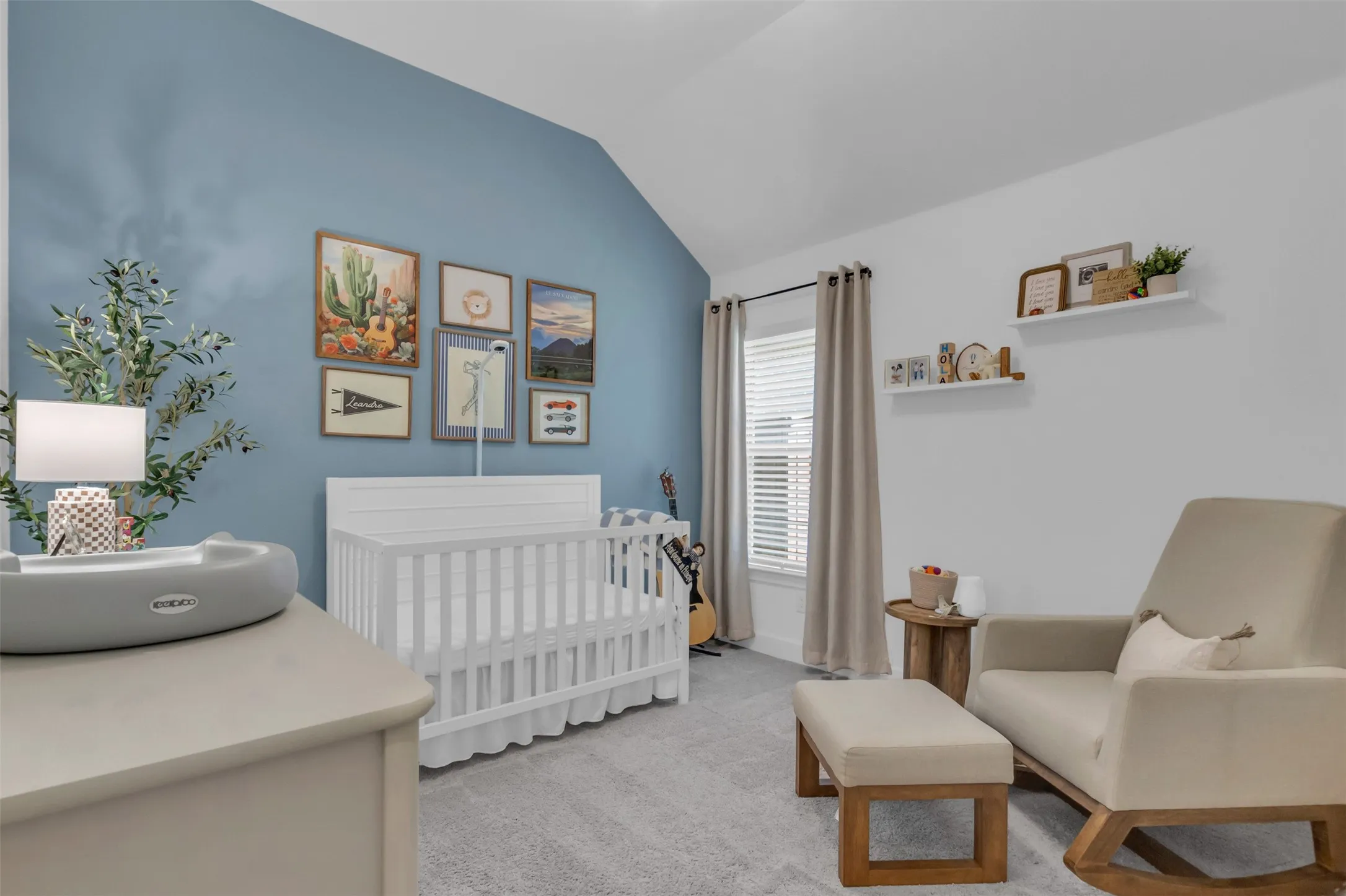 Spacious room featuring vaulted ceilings, a prominent window with blinds, and light gray carpeting