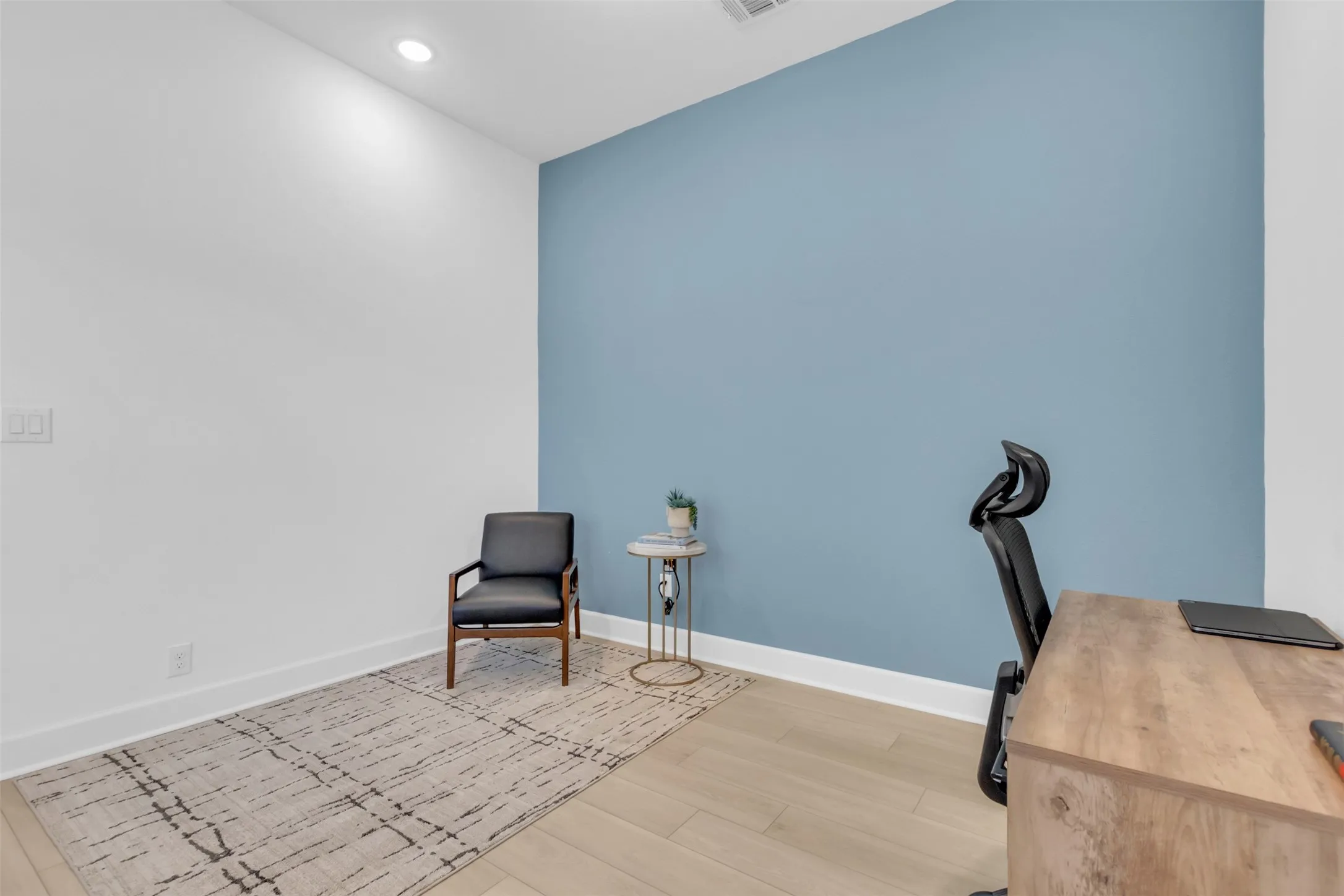 Room featuring a contrasting accent wall, wood-finish flooring, recessed lighting, and crisp white baseboards