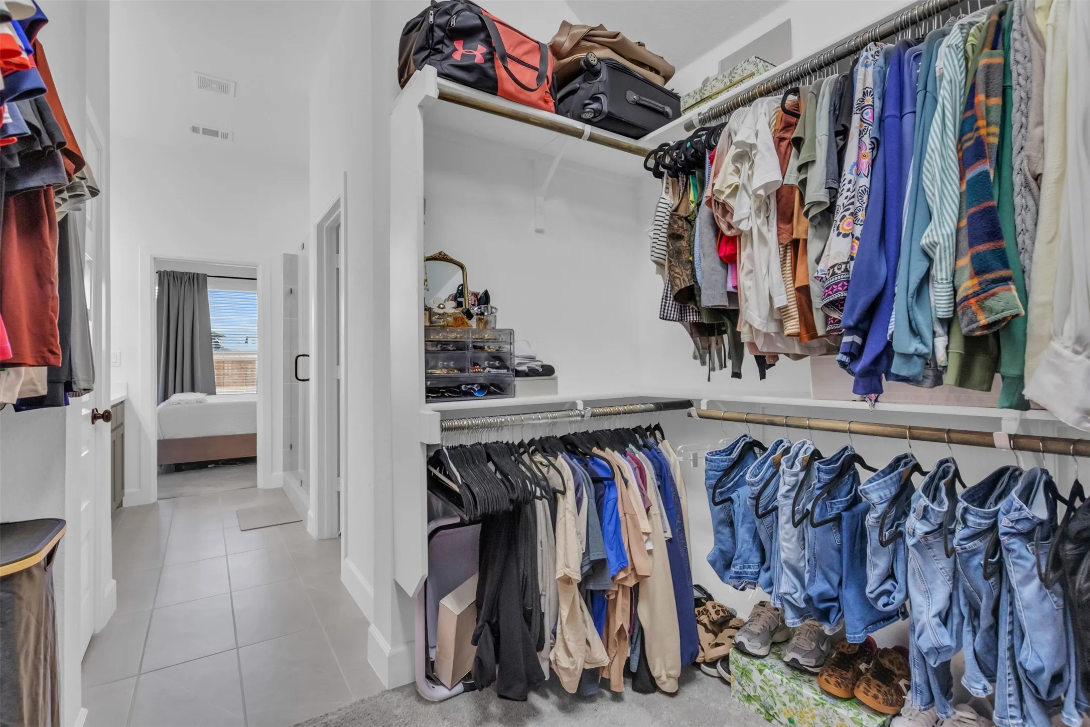 Spacious walk-in closet featuring multiple shelving units, garment rods, and light-toned tile flooring
