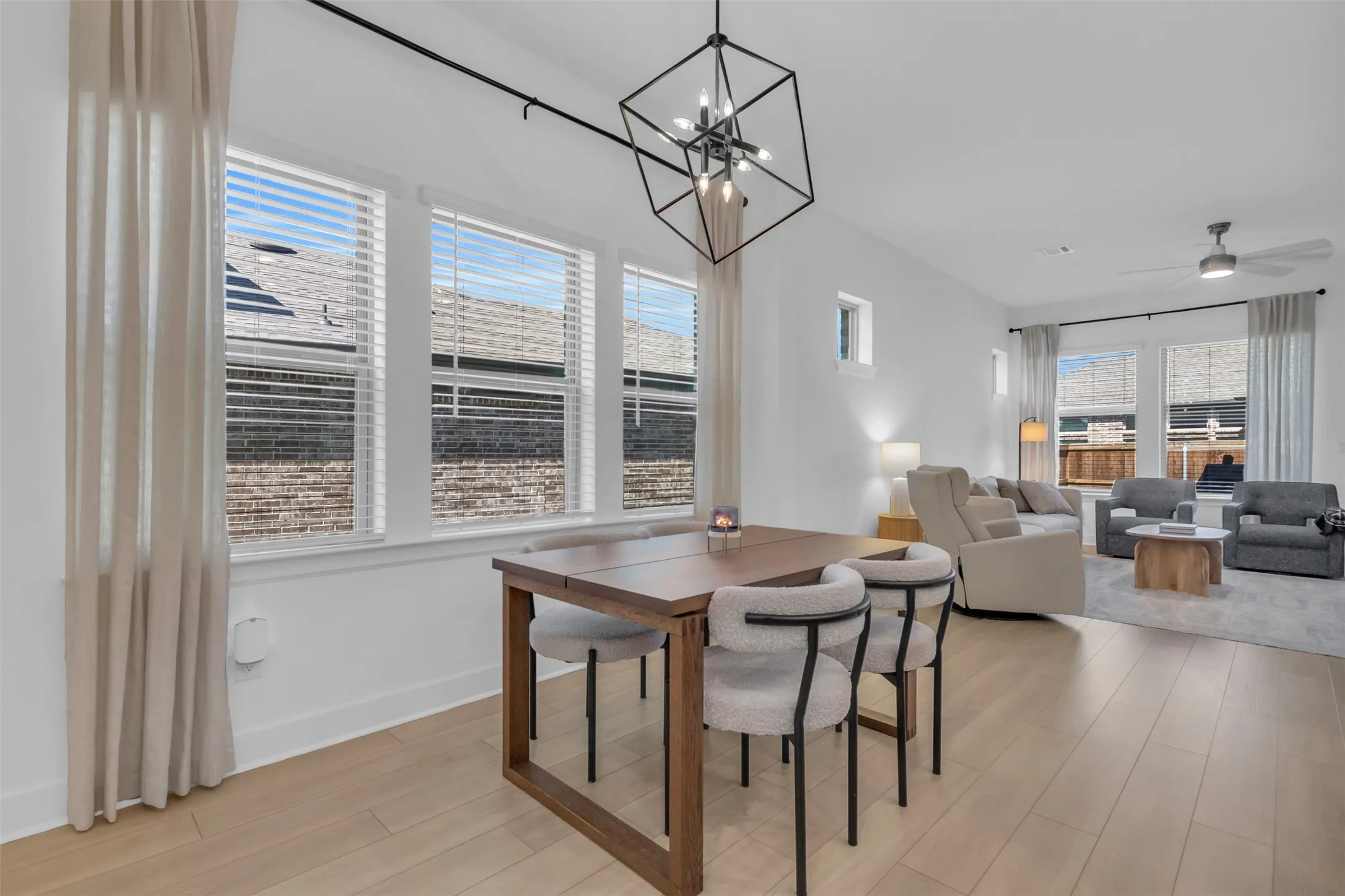 Open-concept living area featuring light wood-finish flooring, white walls, and abundant natural light from multiple windows