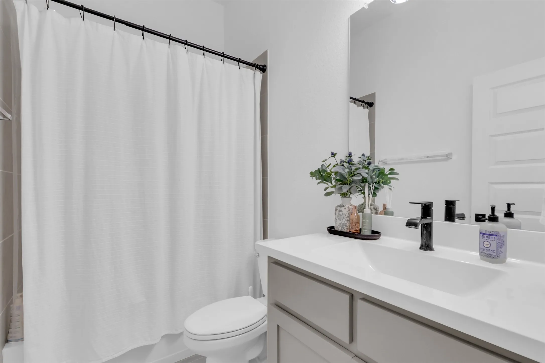 Bathroom featuring a white shower curtain, black shower rod, and light-colored wall tiles