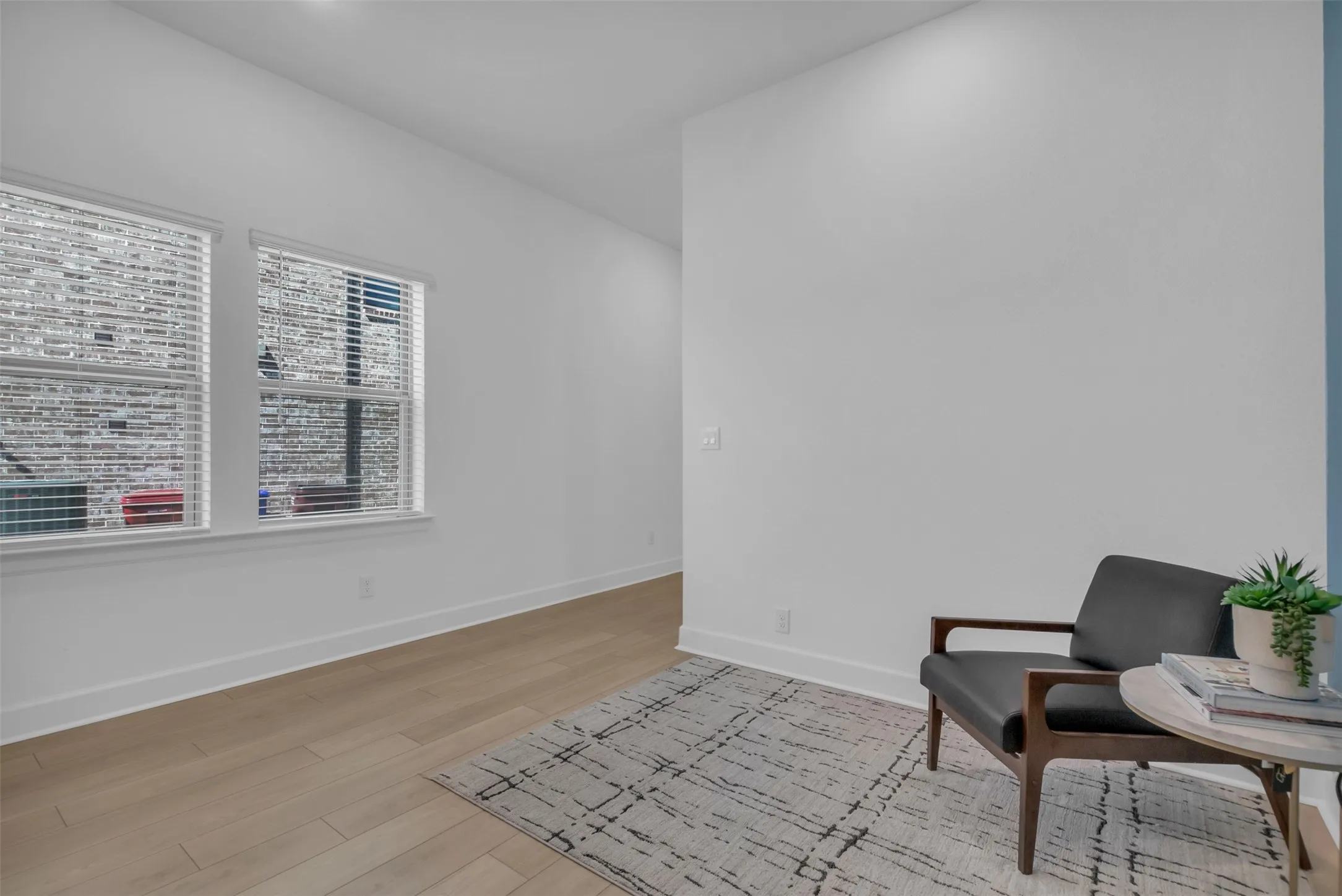 Bright interior space featuring light wood-finish flooring, white baseboards, and white walls