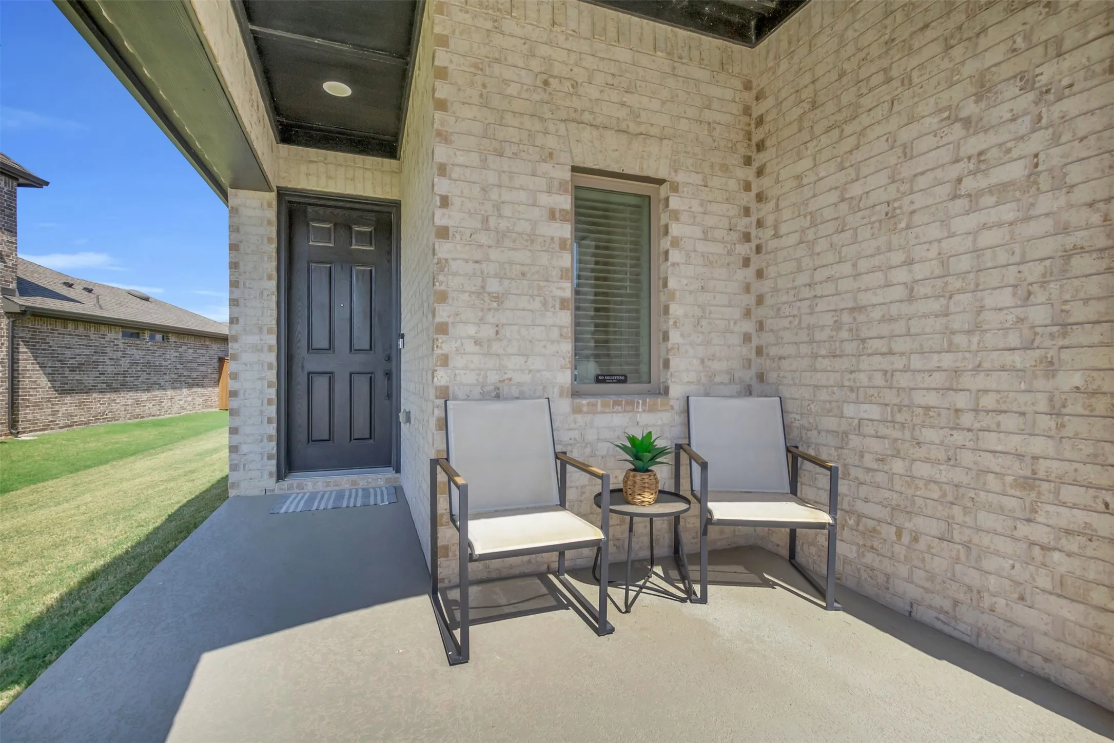 Covered patio featuring a brick exterior, paneled entry door, and a built-in window