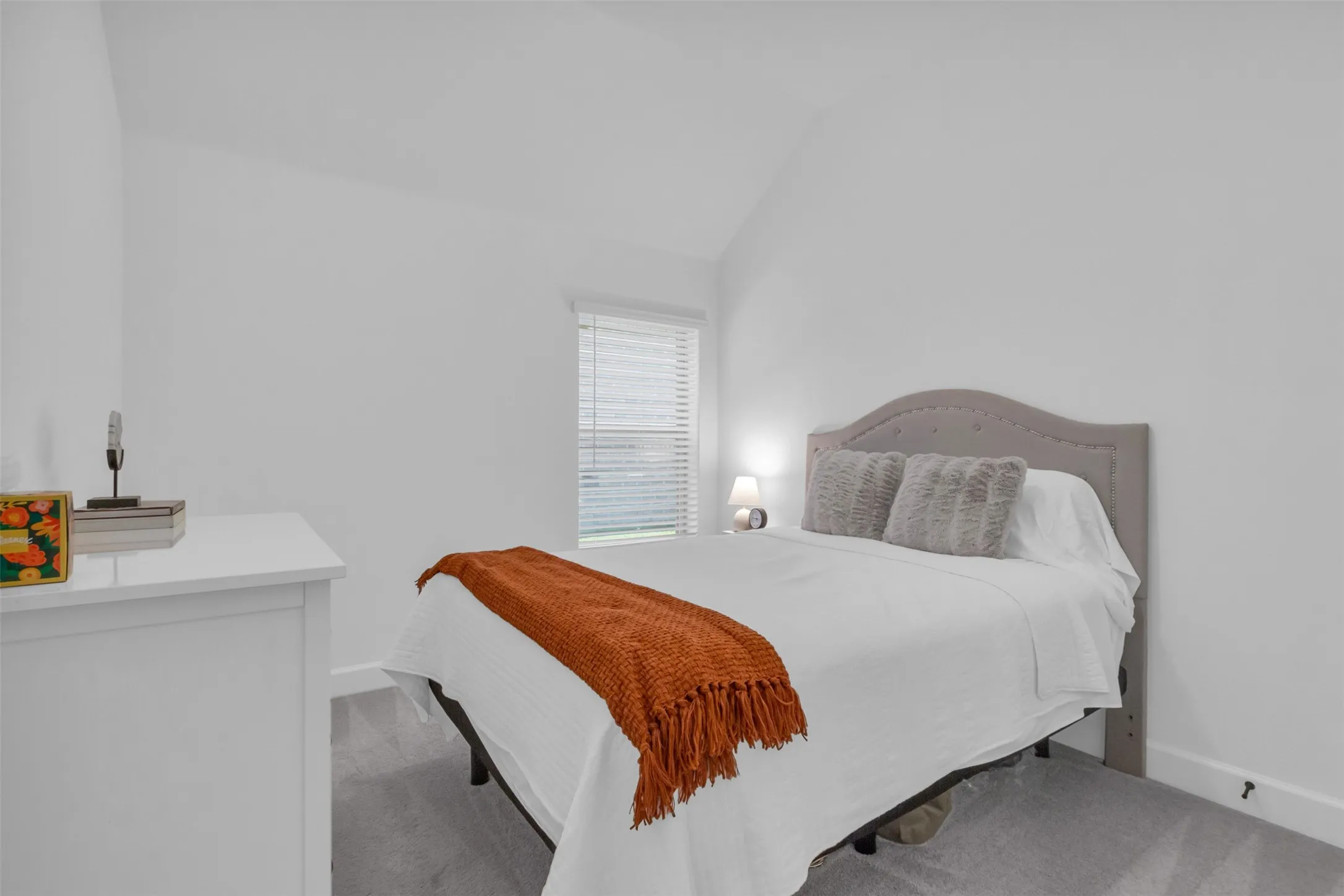 Vaulted ceiling bedroom with light gray carpeting and white walls