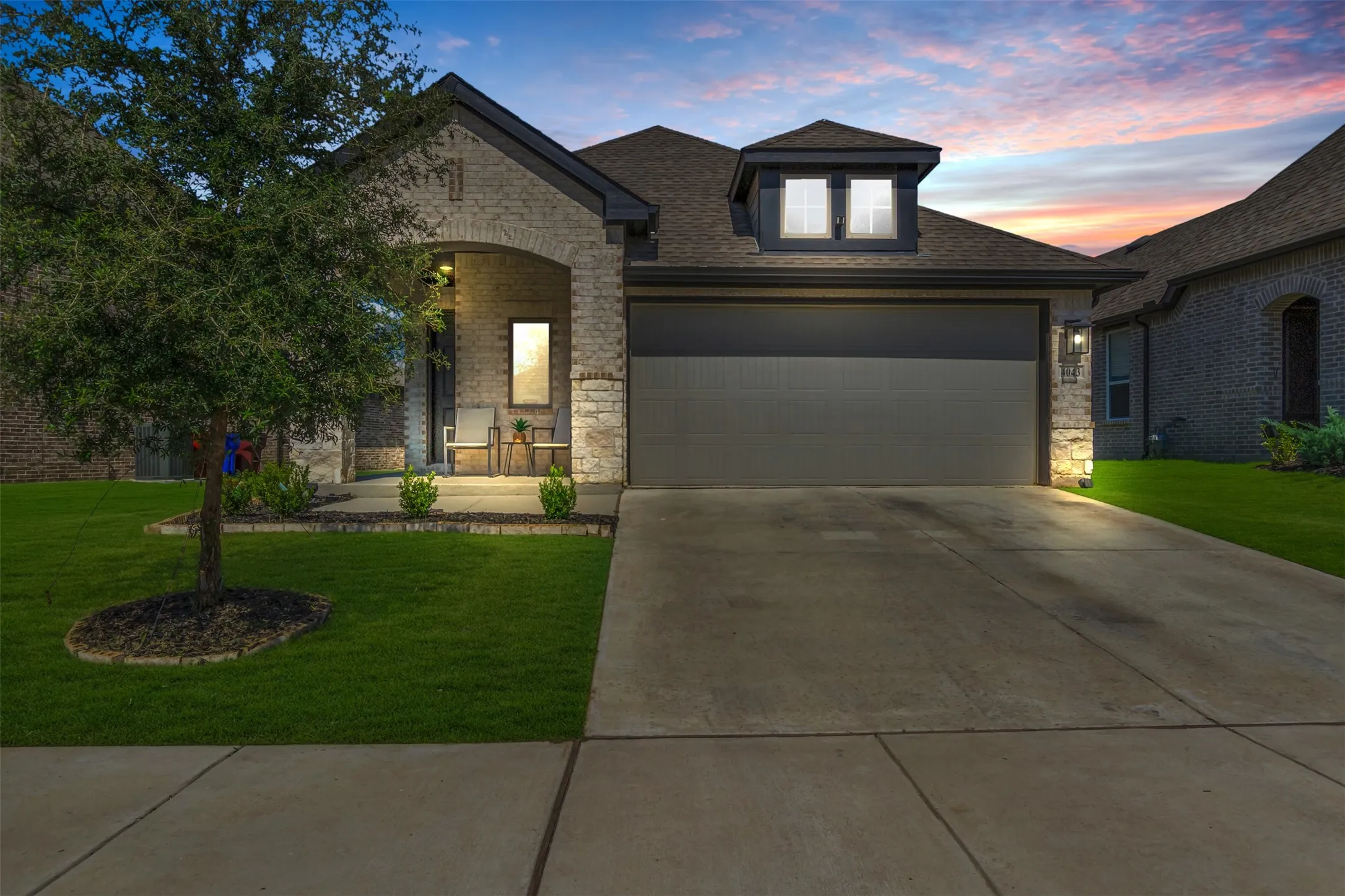 Single-story residence featuring a combination stone and brick facade, an arched entry porch, and a two-car garage with a modern door