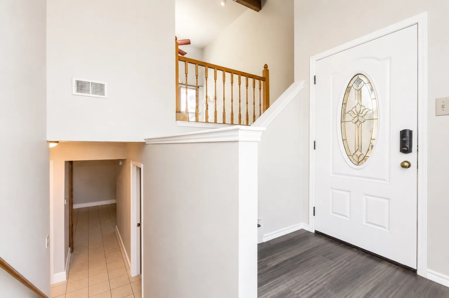 Entryway featuring a white paneled door with an oval stained-glass insert, dark wood-finish flooring, and light gray wall paint
