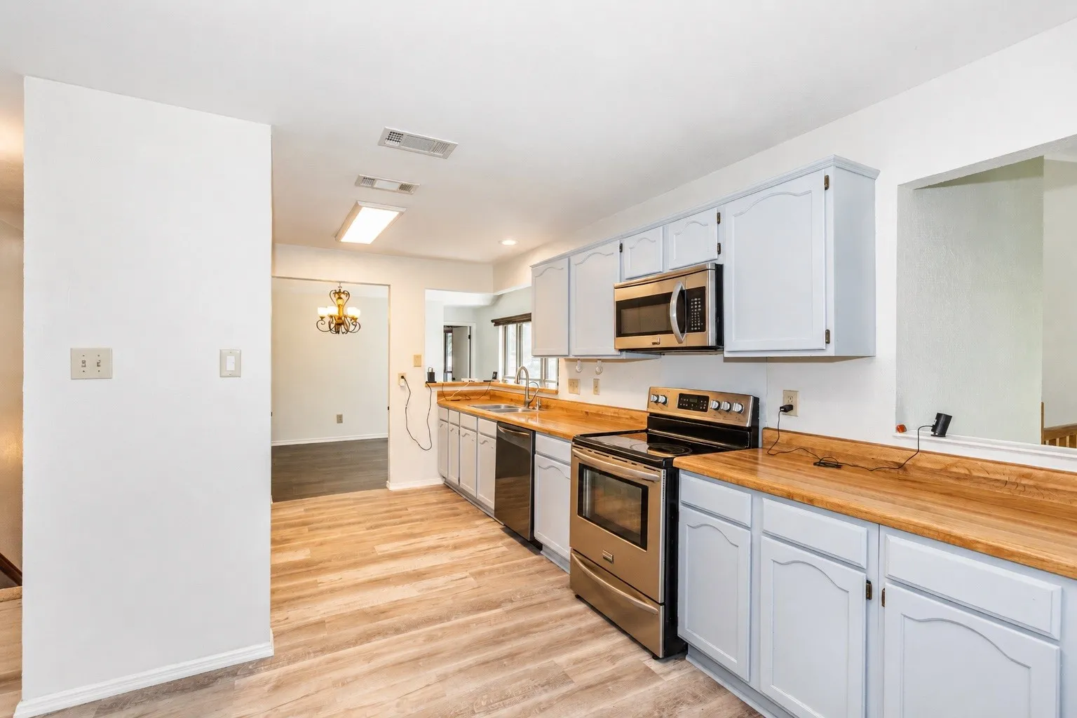 Kitchen featuring wood-finish flooring, light blue cabinetry, and wood-finish countertops