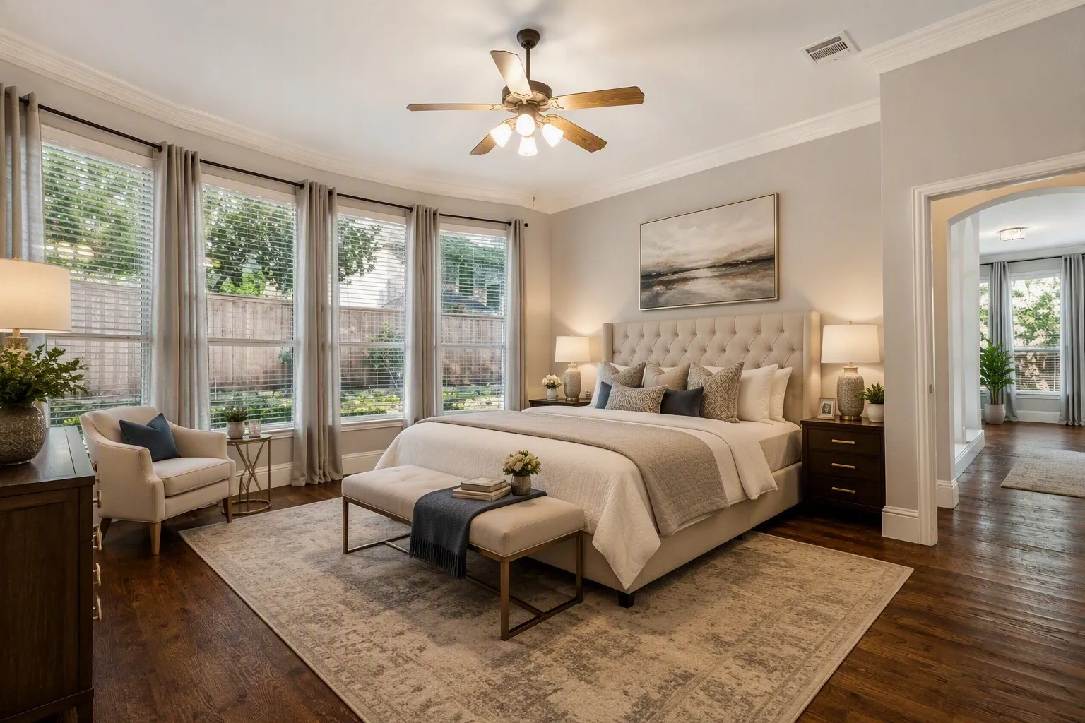 Rich wood-finish flooring, a ceiling fan, crown molding, and a wide arched entryway