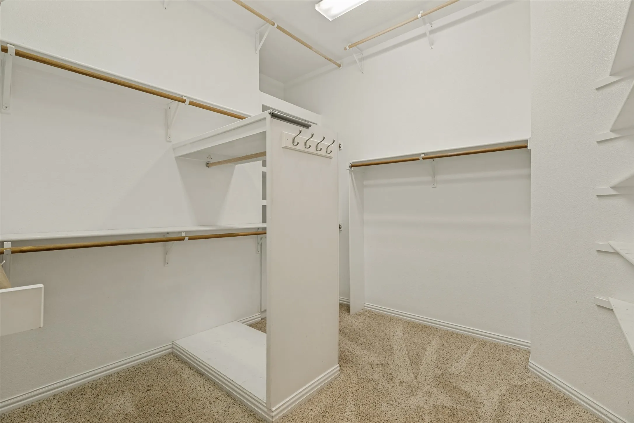 Custom closet system with multiple shelving units, hanging rods, built-in storage, and carpet flooring