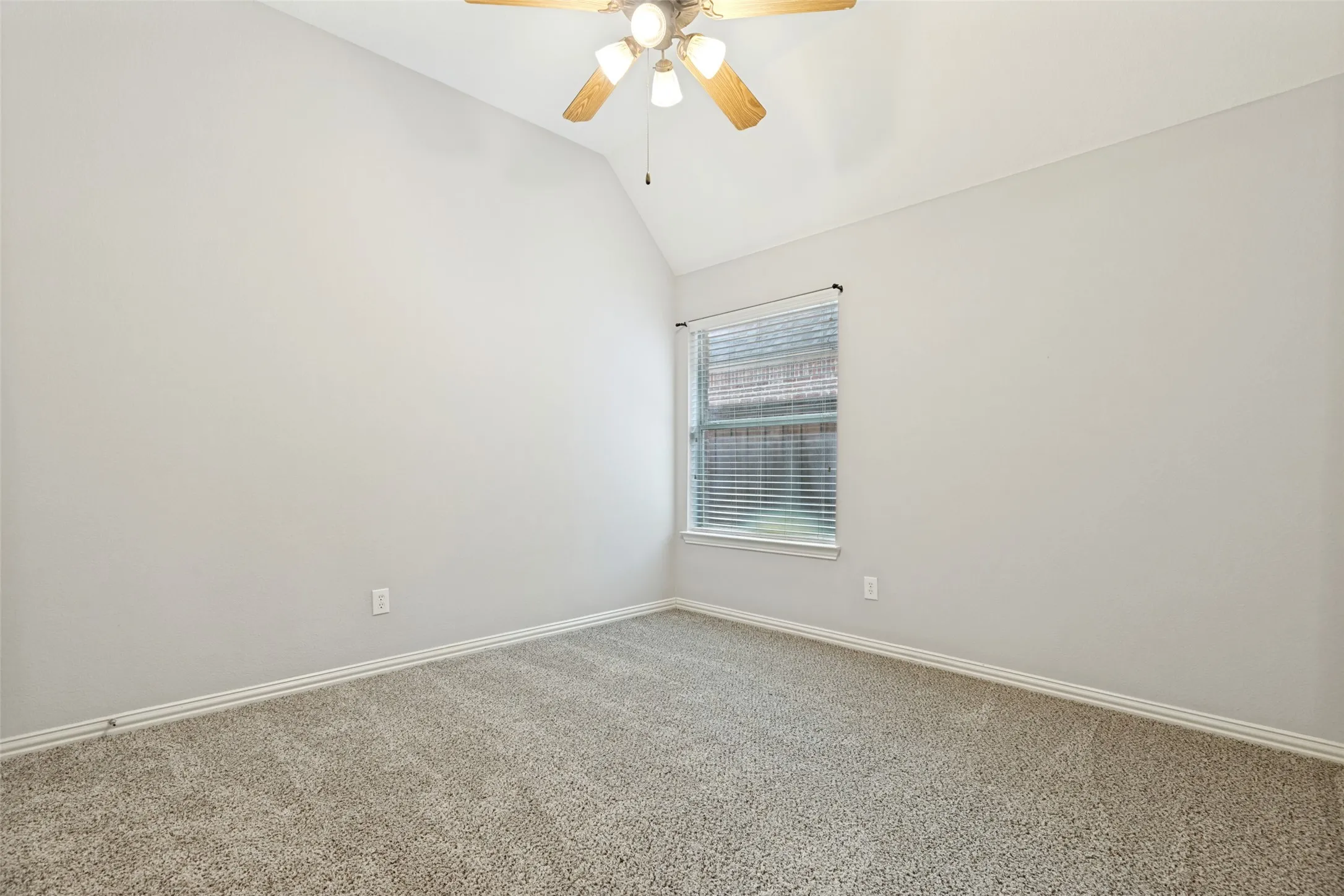 Vaulted ceiling with an attached ceiling fan, single window with blinds, and carpet flooring