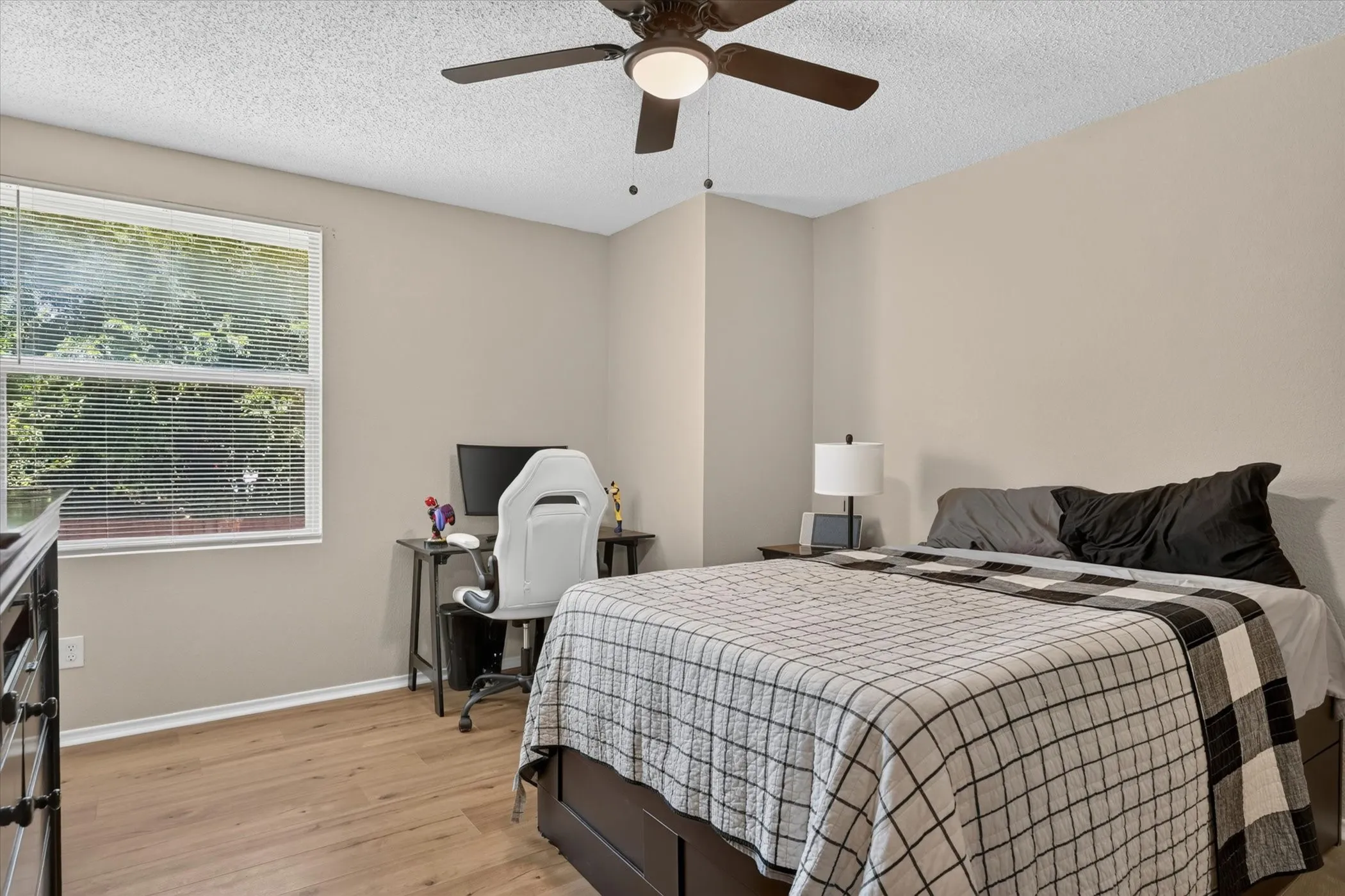 Bedroom featuring wood-finish flooring, a ceiling fan with integrated lighting, and a large window with blinds