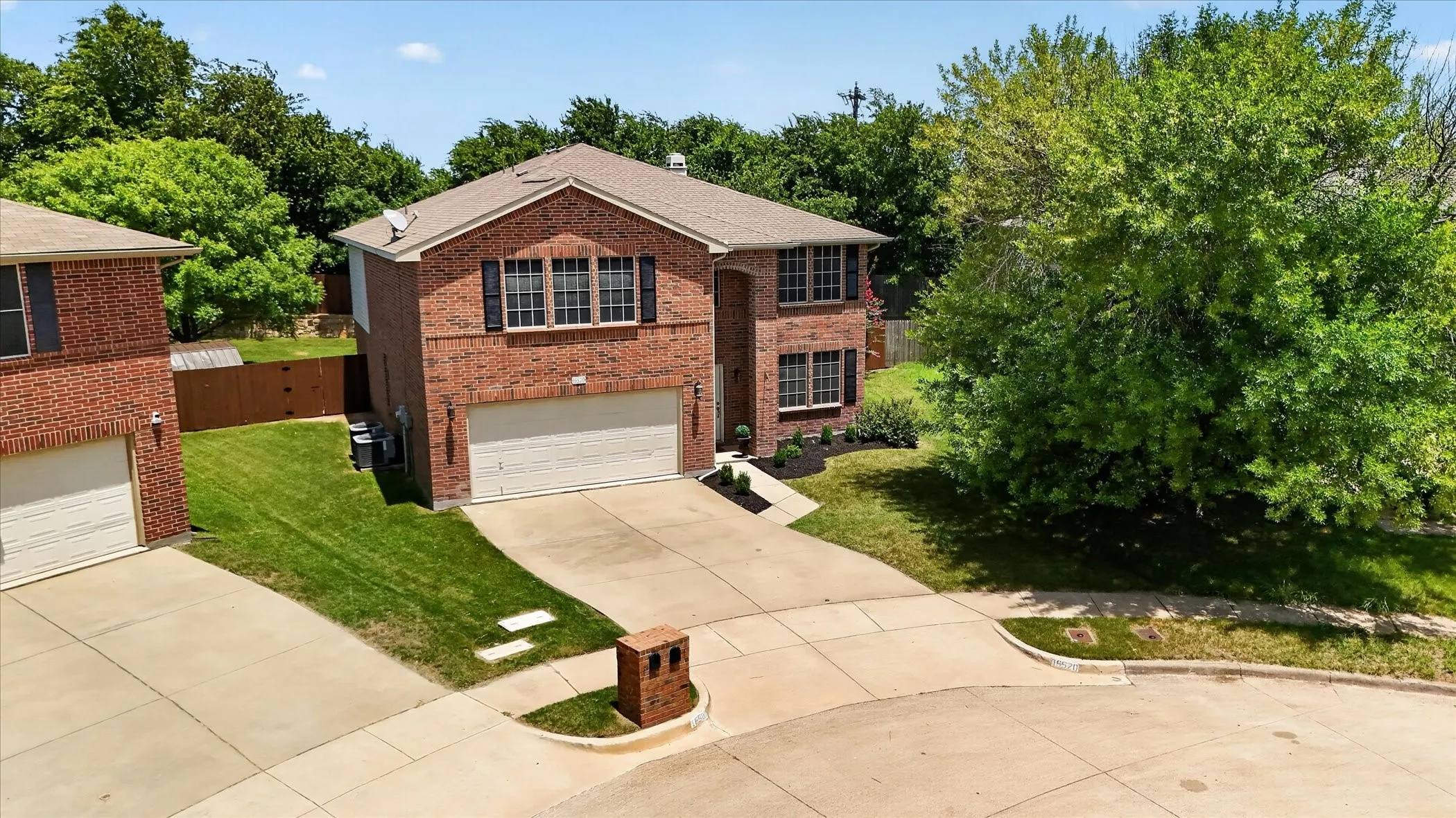 Two-story brick exterior featuring a multi-pane window design with shutters, an attached two-car garage, and a dedicated driveway