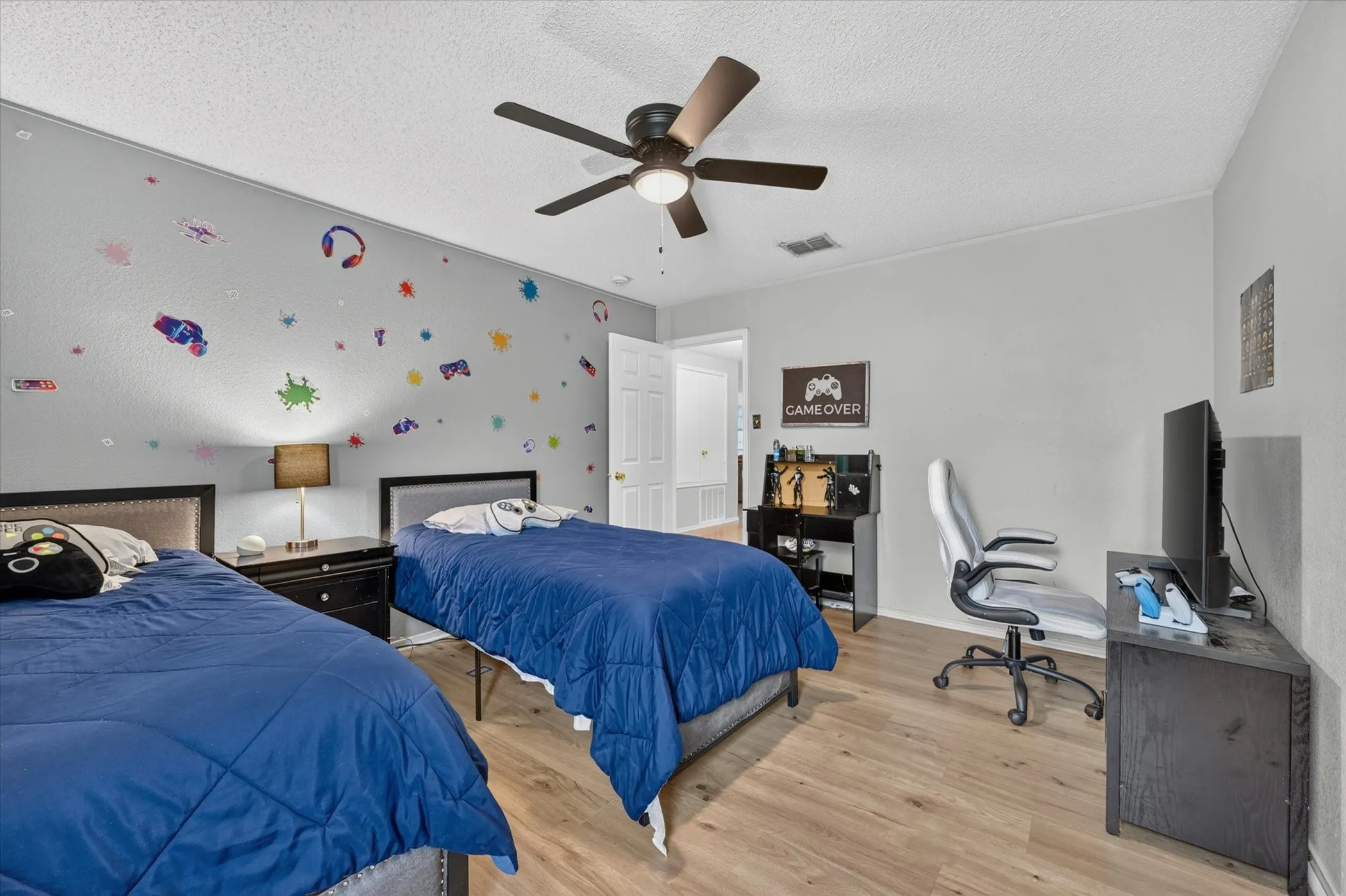 Spacious room featuring wood-finish flooring, a ceiling fan, and light gray walls