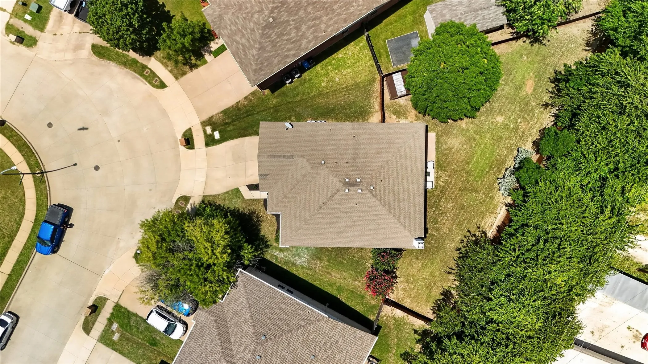 Property with a gabled roof and a spacious backyard featuring mature trees