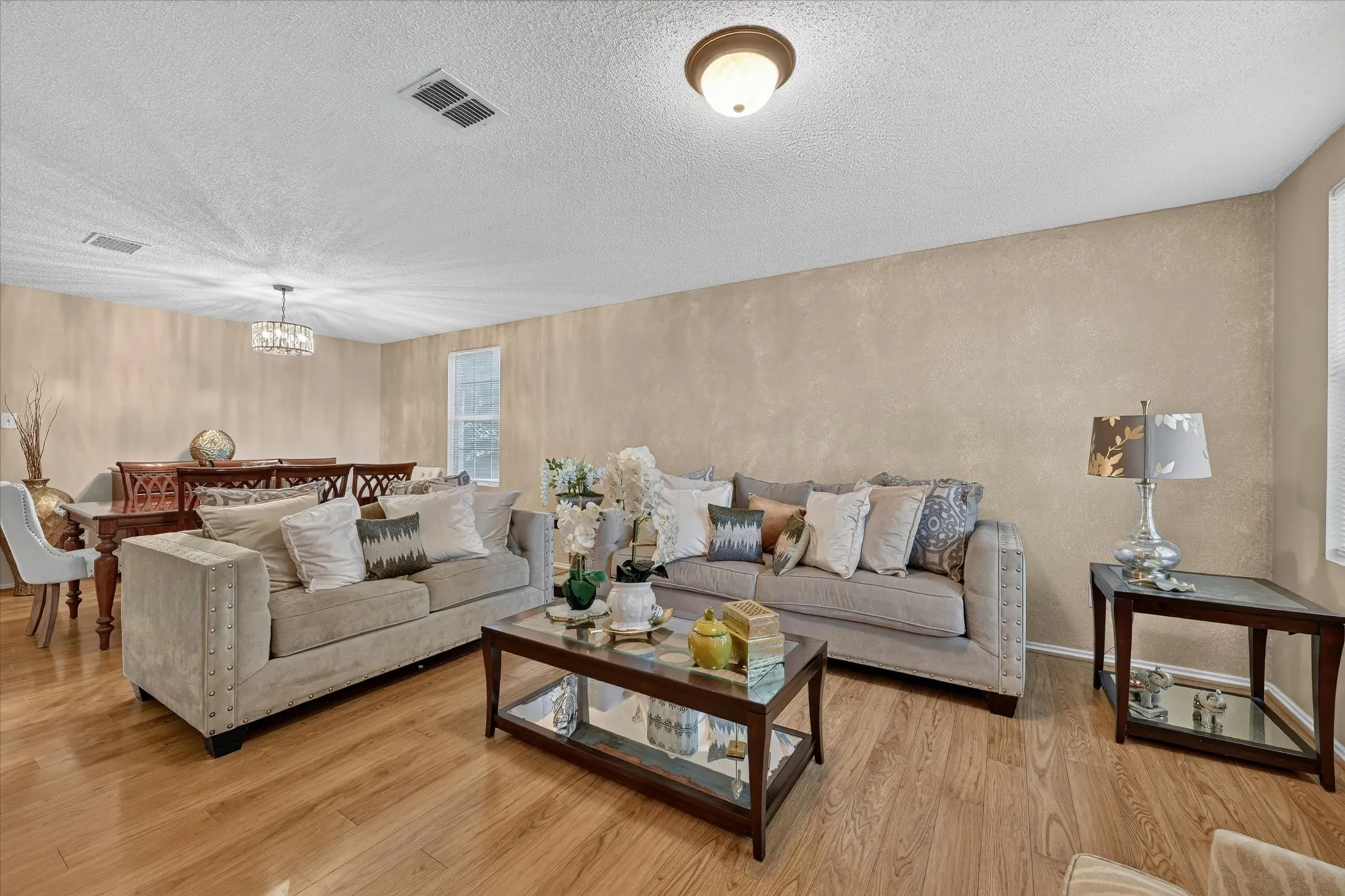 Open-concept living space featuring wood-finish flooring, textured wall finishes, and recessed lighting