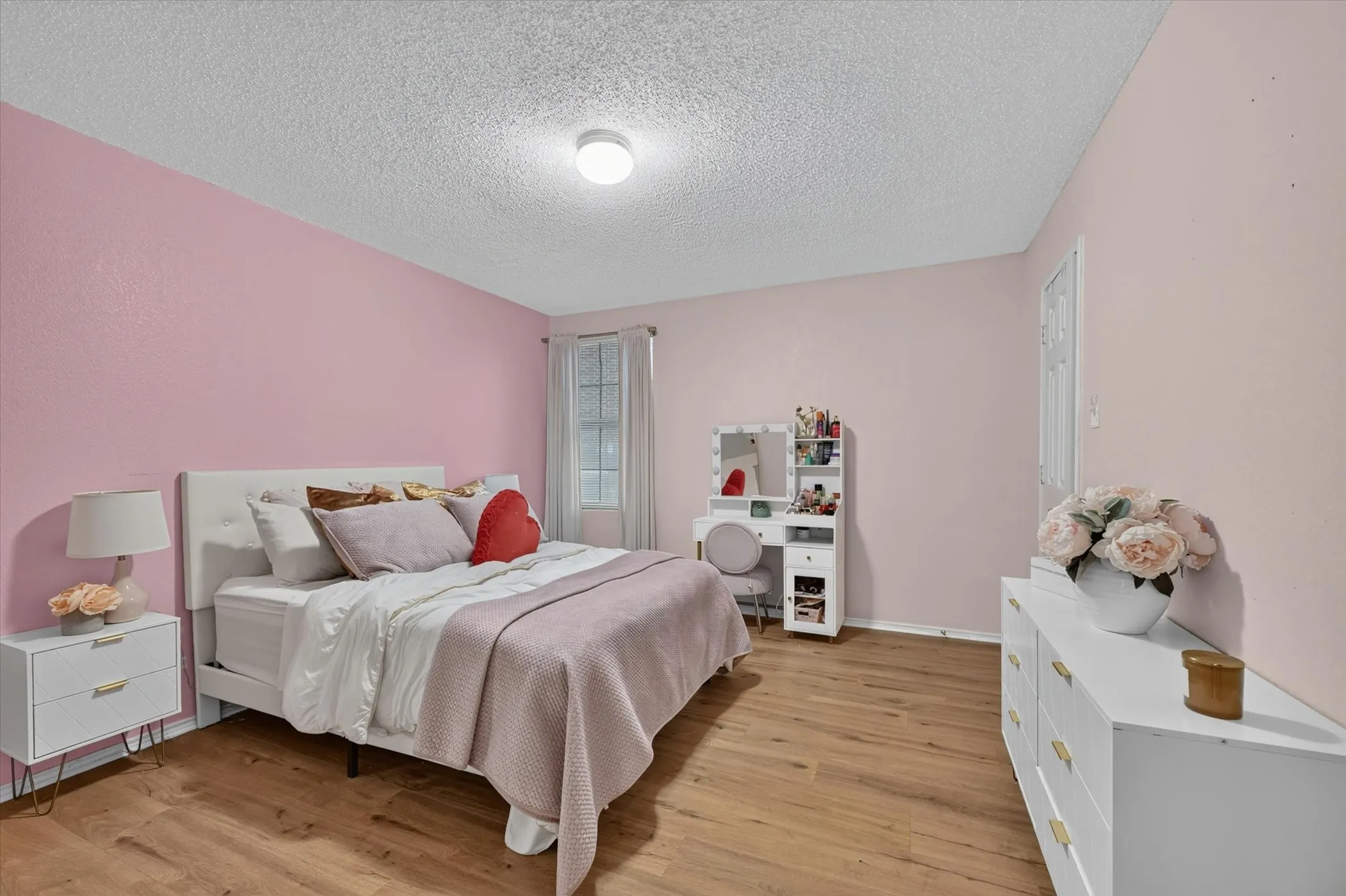 Bedroom featuring light pink walls and wood-finish flooring