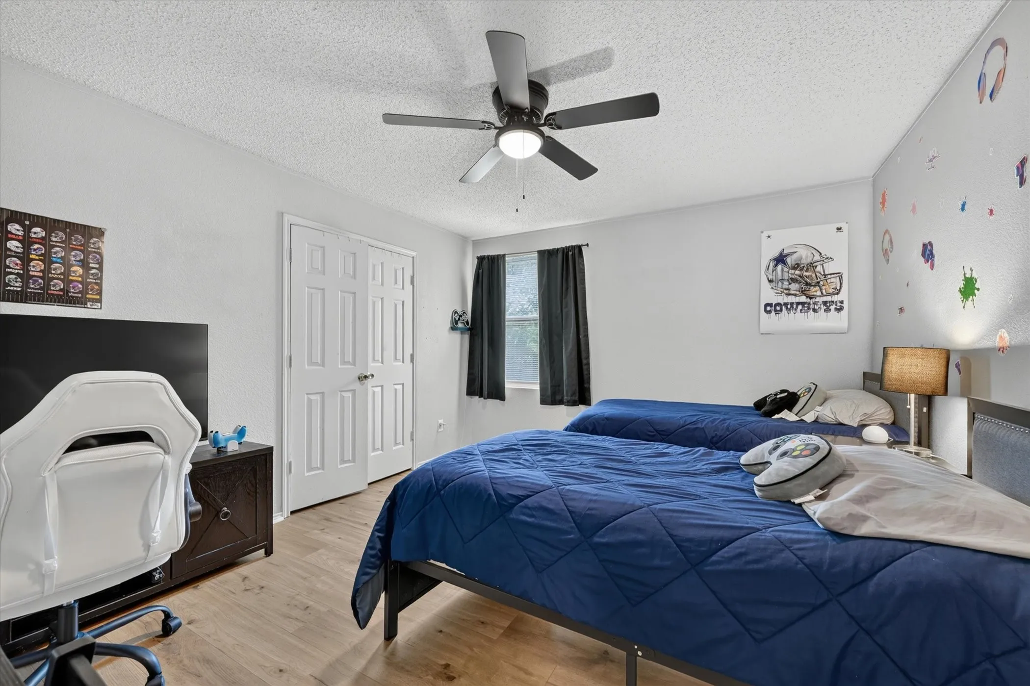 Interior room featuring wood-finish flooring, light grey walls, and a ceiling fan with integrated lighting
