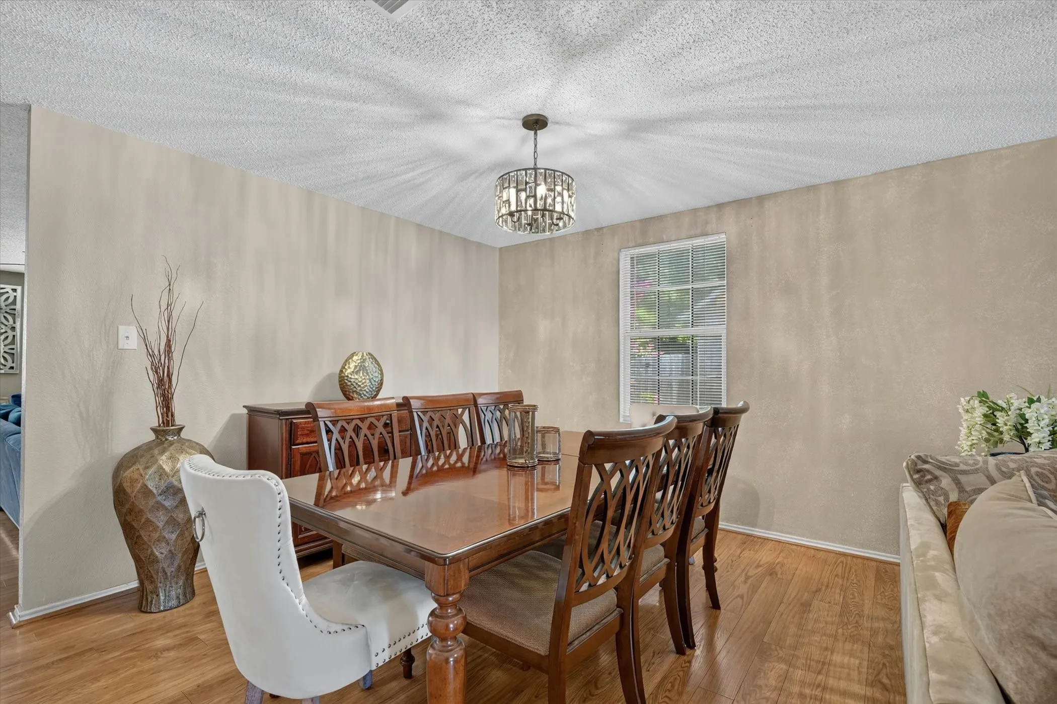 Dining area with wood-finish flooring, a contemporary chandelier, and a window providing natural light