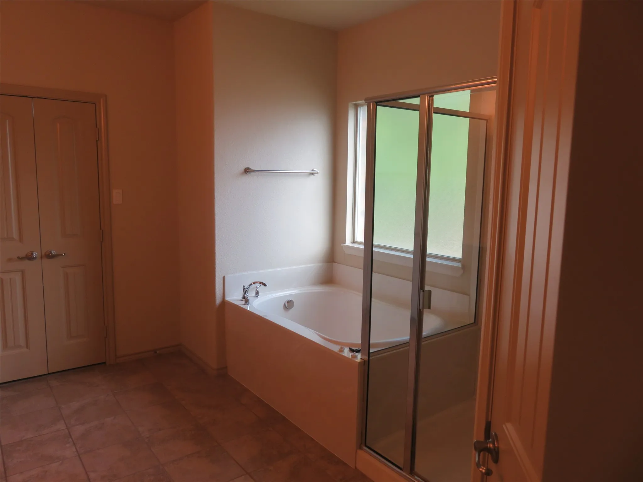 Bathroom featuring a soaking tub with mounted fixtures, a clear glass shower enclosure, and a window with privacy glass