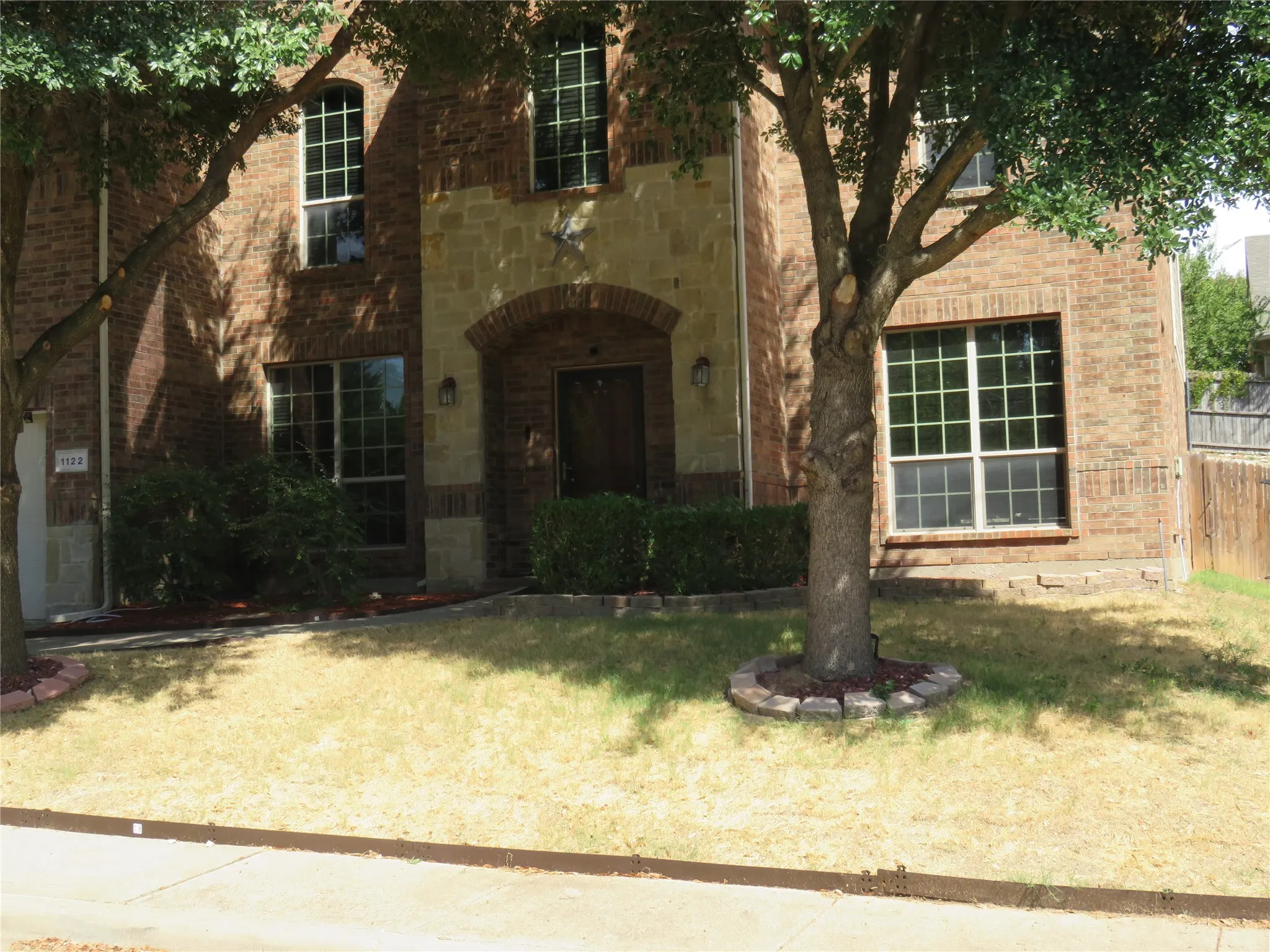 Brick facade with stone accents, arched entryway, and multiple grid-pattern windows