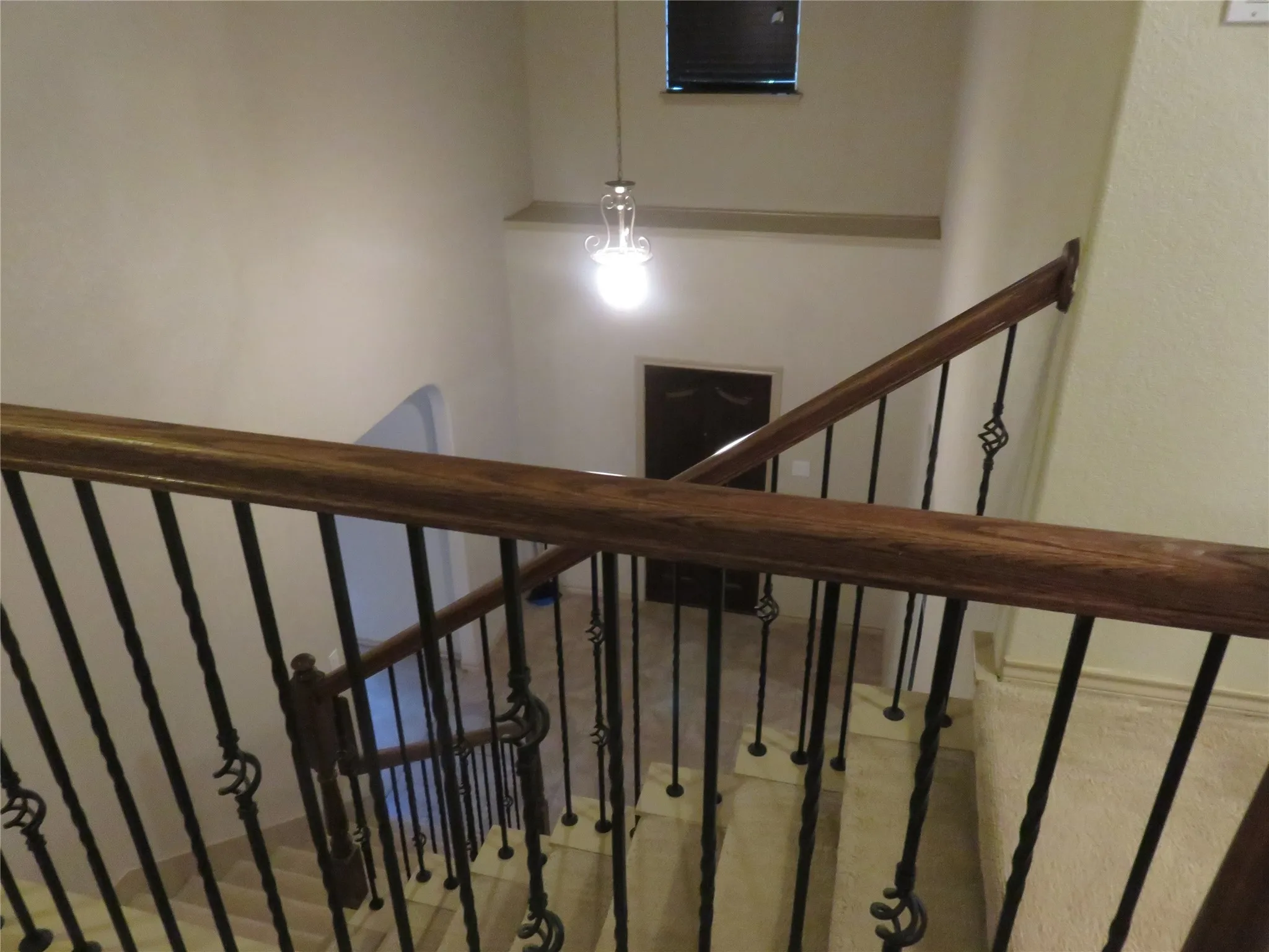 Staircase featuring wrought iron balusters with decorative elements, a polished wood handrail, and tiled steps