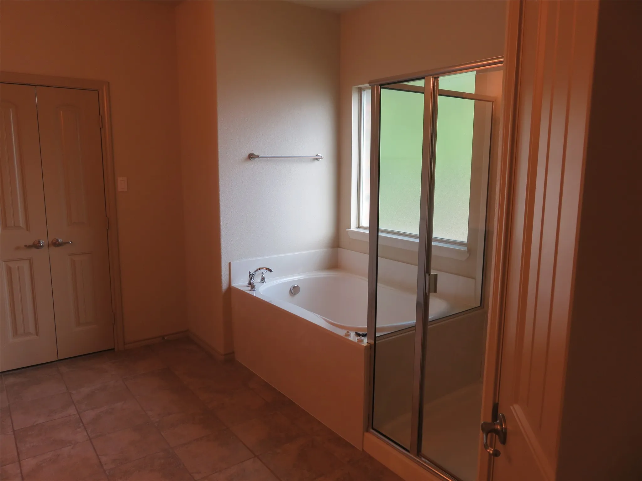 Bathroom featuring a built-in soaking tub, an enclosed shower with a glass door, and a privacy window