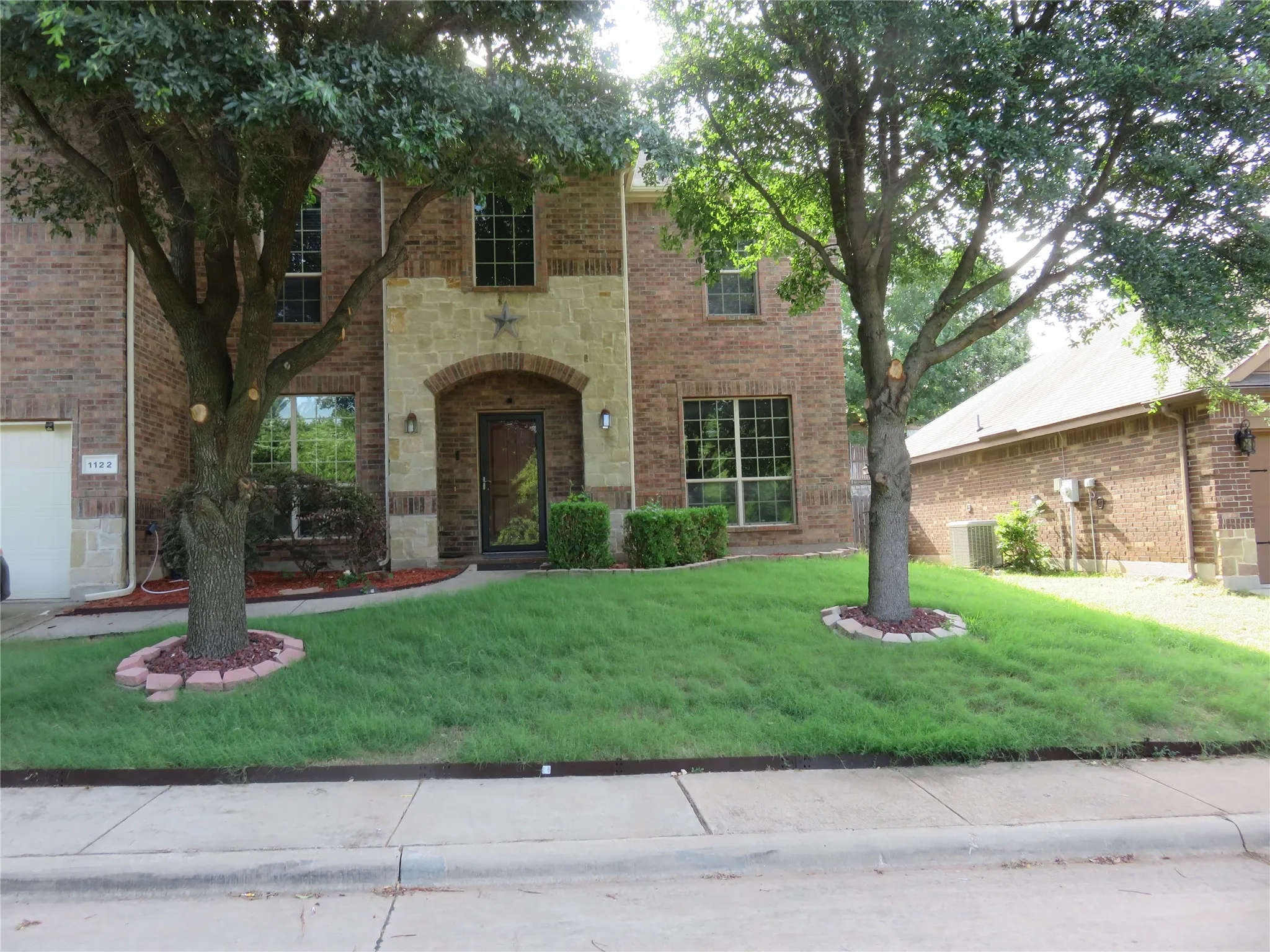 Brick and stone facade featuring an arched entryway with a glass-paneled door