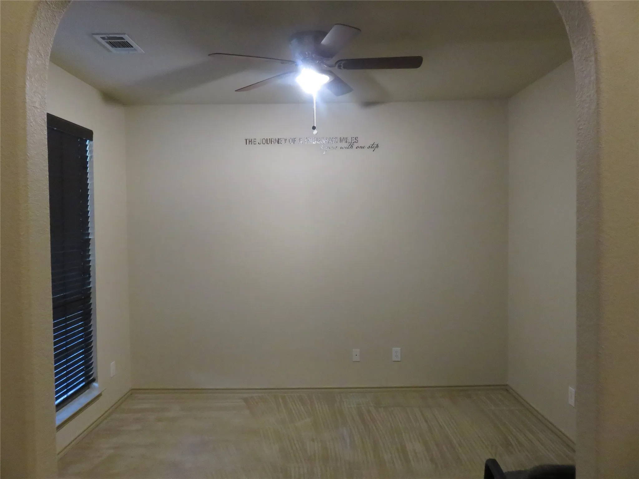 Spacious room featuring neutral-toned walls and wood-finish flooring